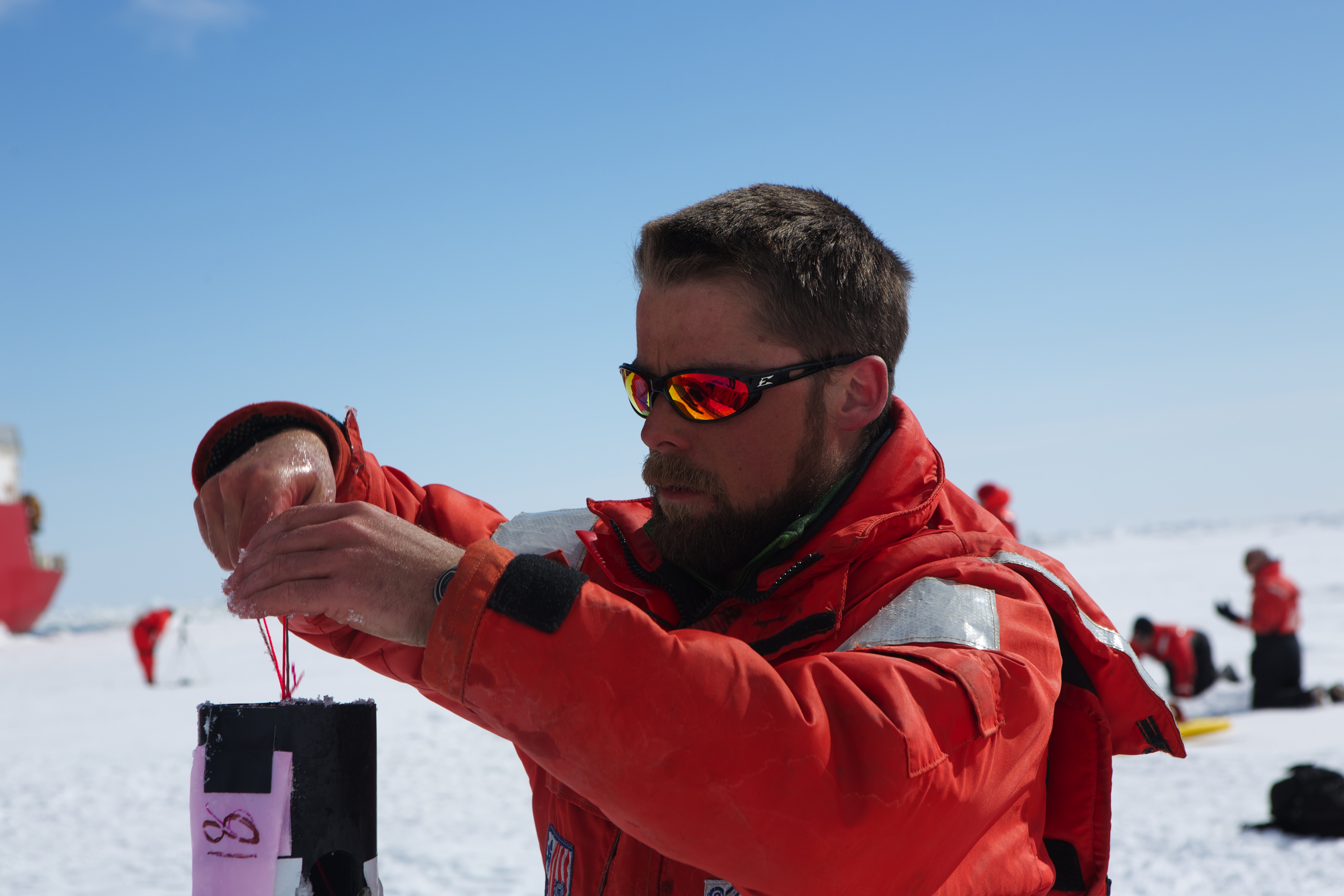 Geophysicist Chris Polashenski drops a pressure sensor into a plastic tube that he's using for his research into melt ponds that form on the Arctic ice every spring.