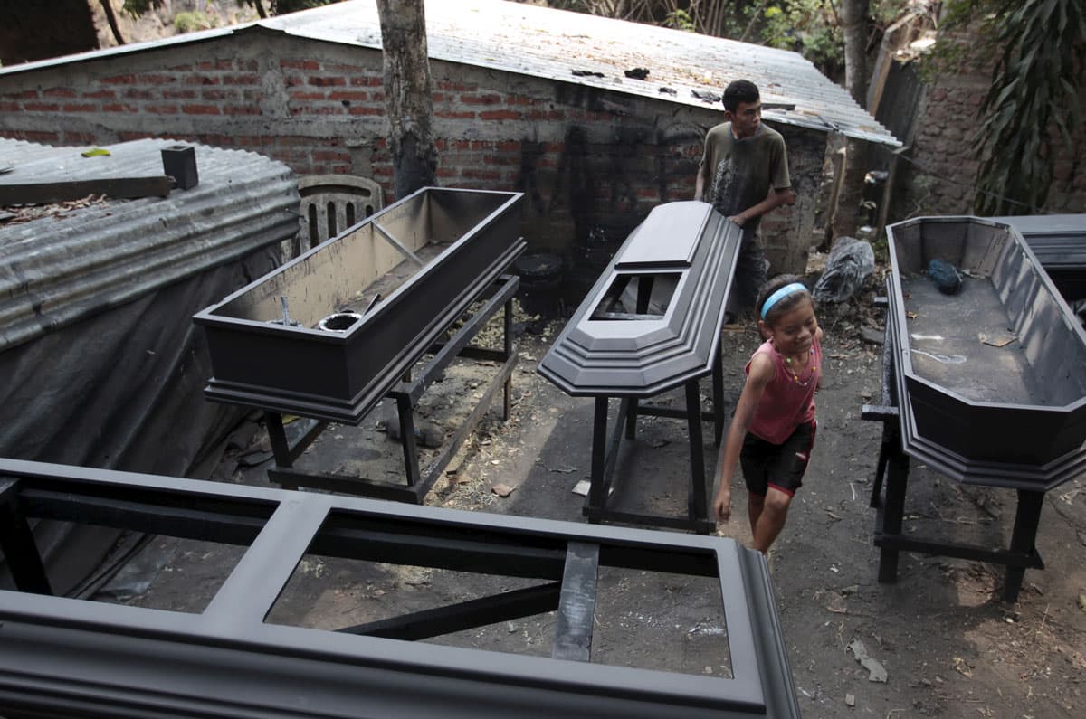 A worker applies sealant to a coffin at El Nuevo Renacer factory in Jucuapa.