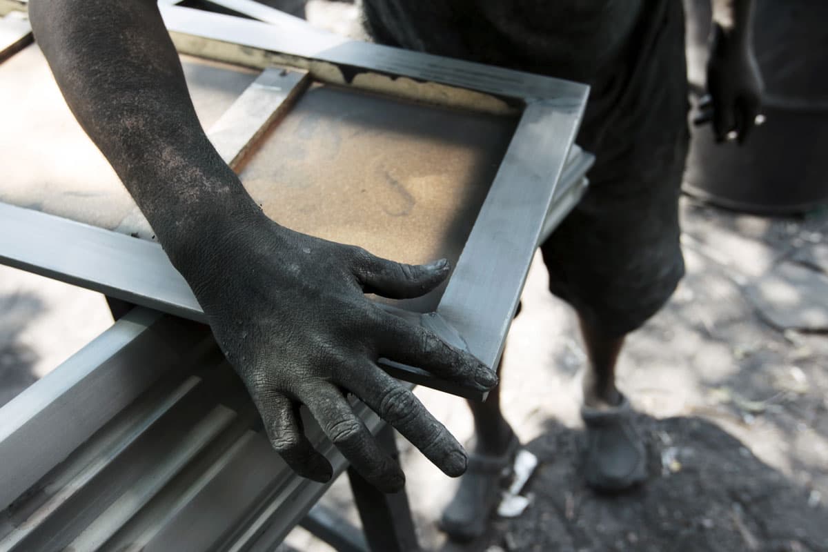 A worker applies sealant to a coffin at El Nuevo Renacer factory in Jucuapa.