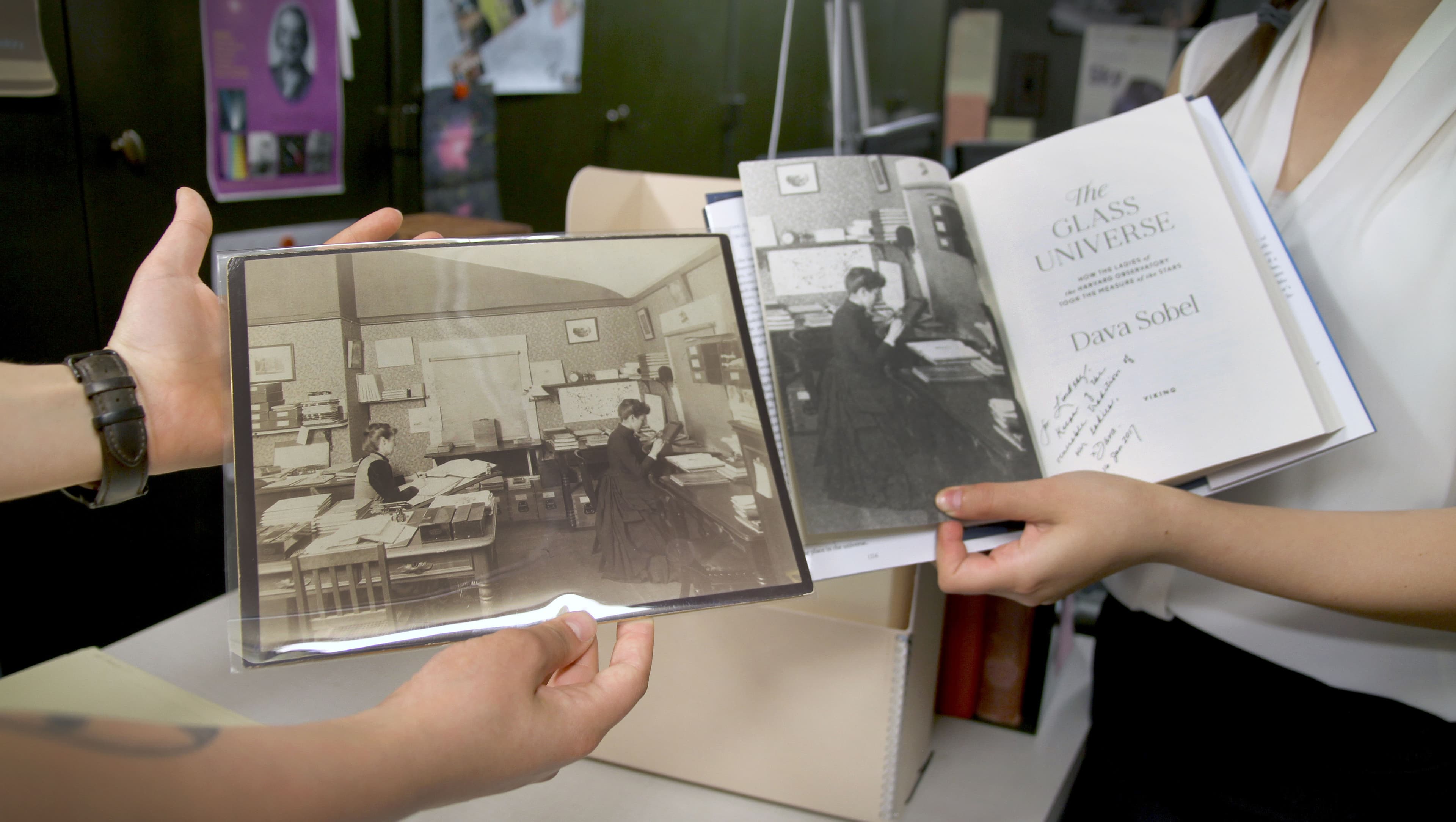 An old photograph of Williamina Fleming posing in 1891 in the plate stacks is held up next to a book with a print of the same image.