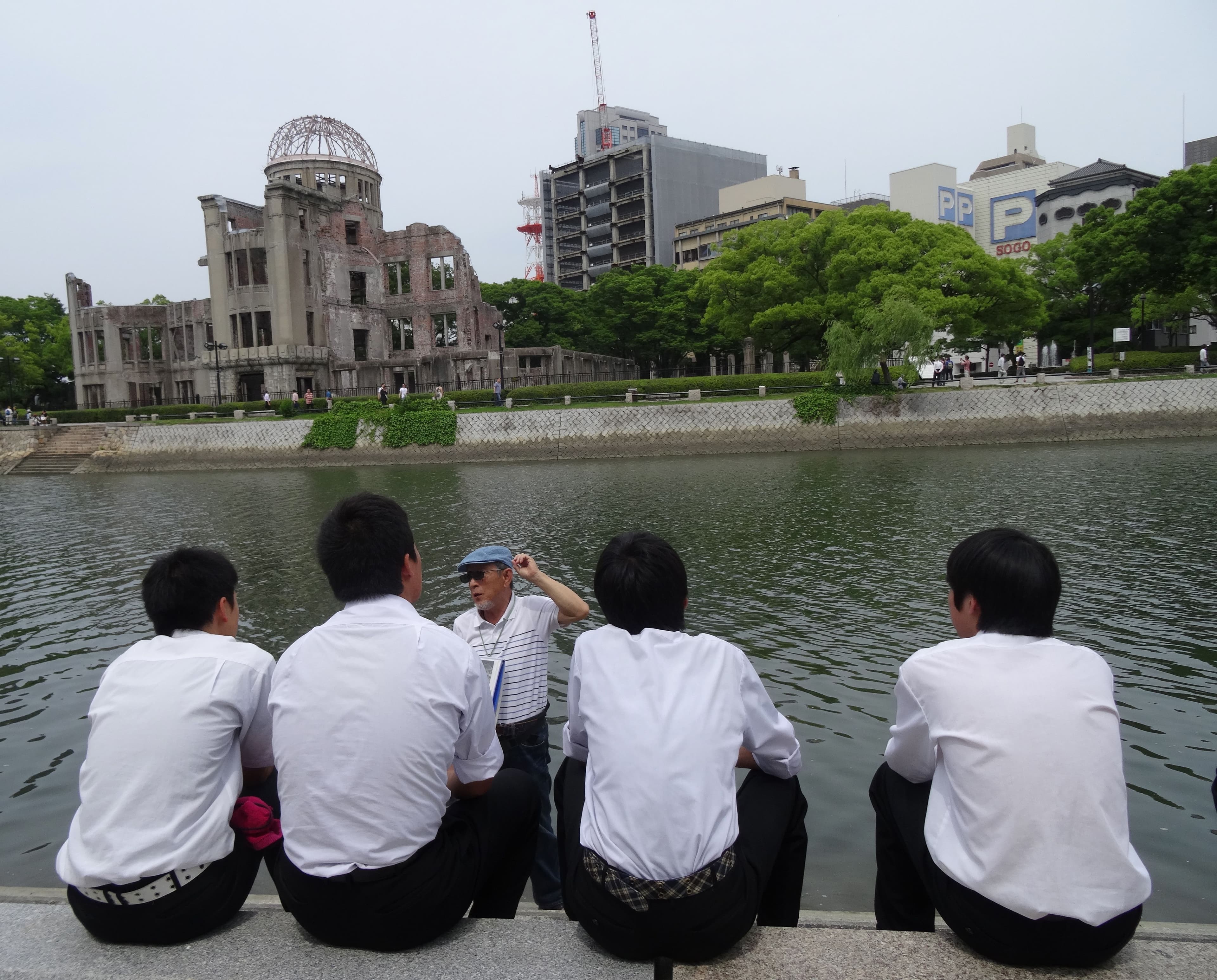 A volunteer guide speaks to school students across the river from the Atomic Bomb Dome in Hiroshima's Peace Memorial Park.