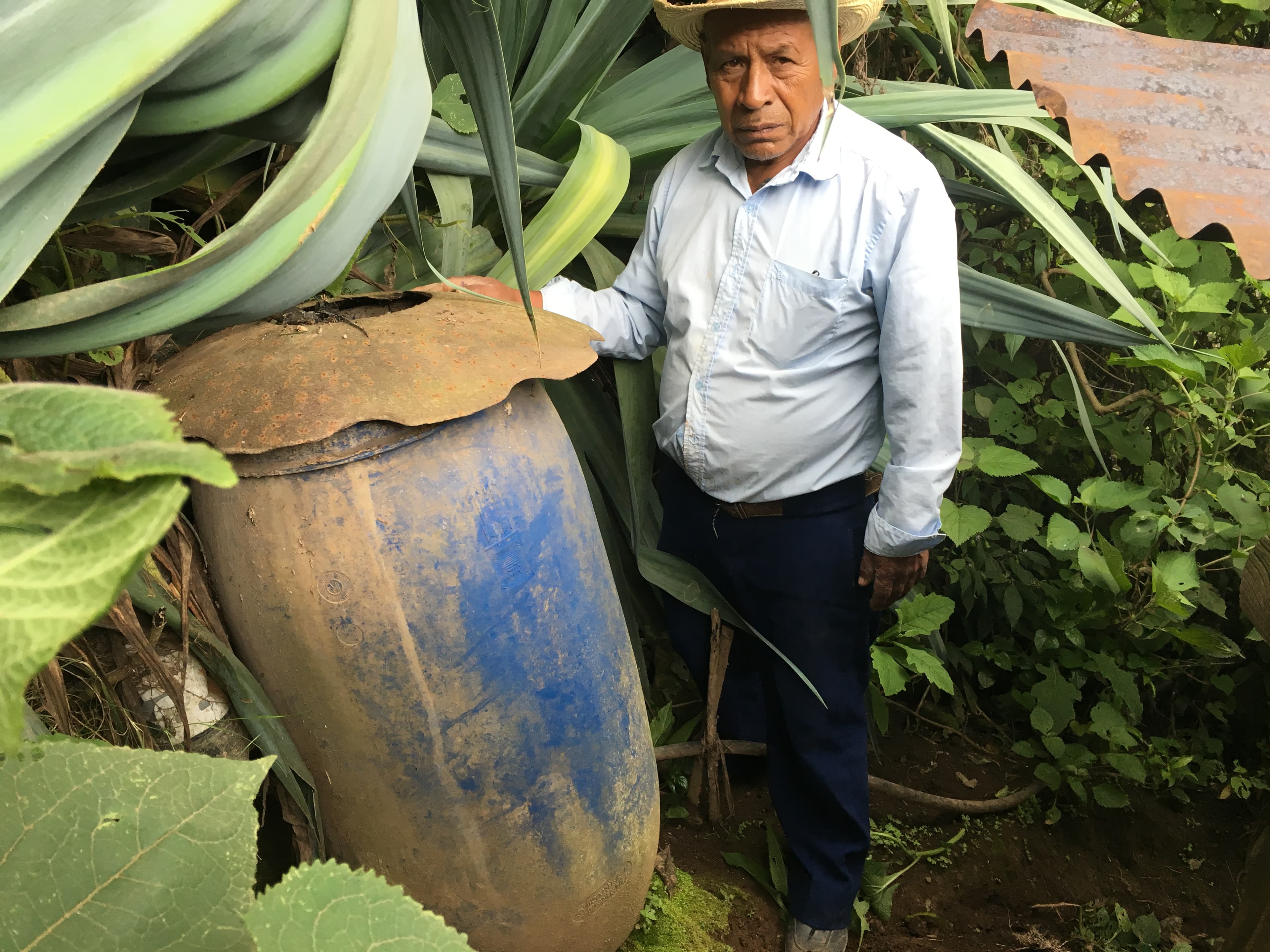 A man stands by a large blue water capture drum.