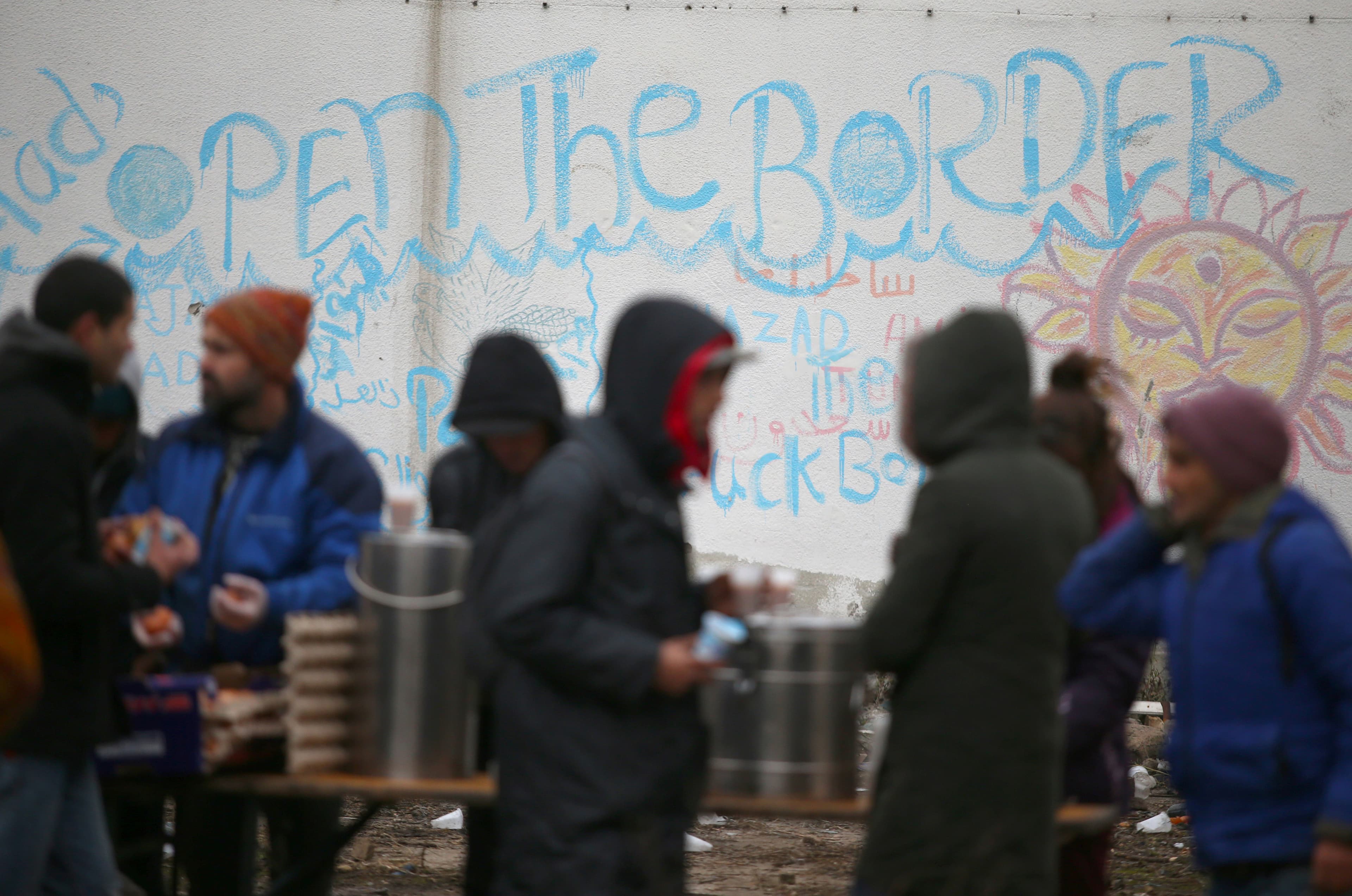 Migrants receive food inside an abandoned factory close to the Croatian border near the town of Sid, Serbia, Dec. 19, 2017.