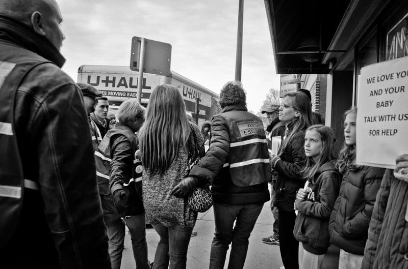 Escorts accompany a patient down the sidewalk and to the doors of the clinic in Milwuakee.