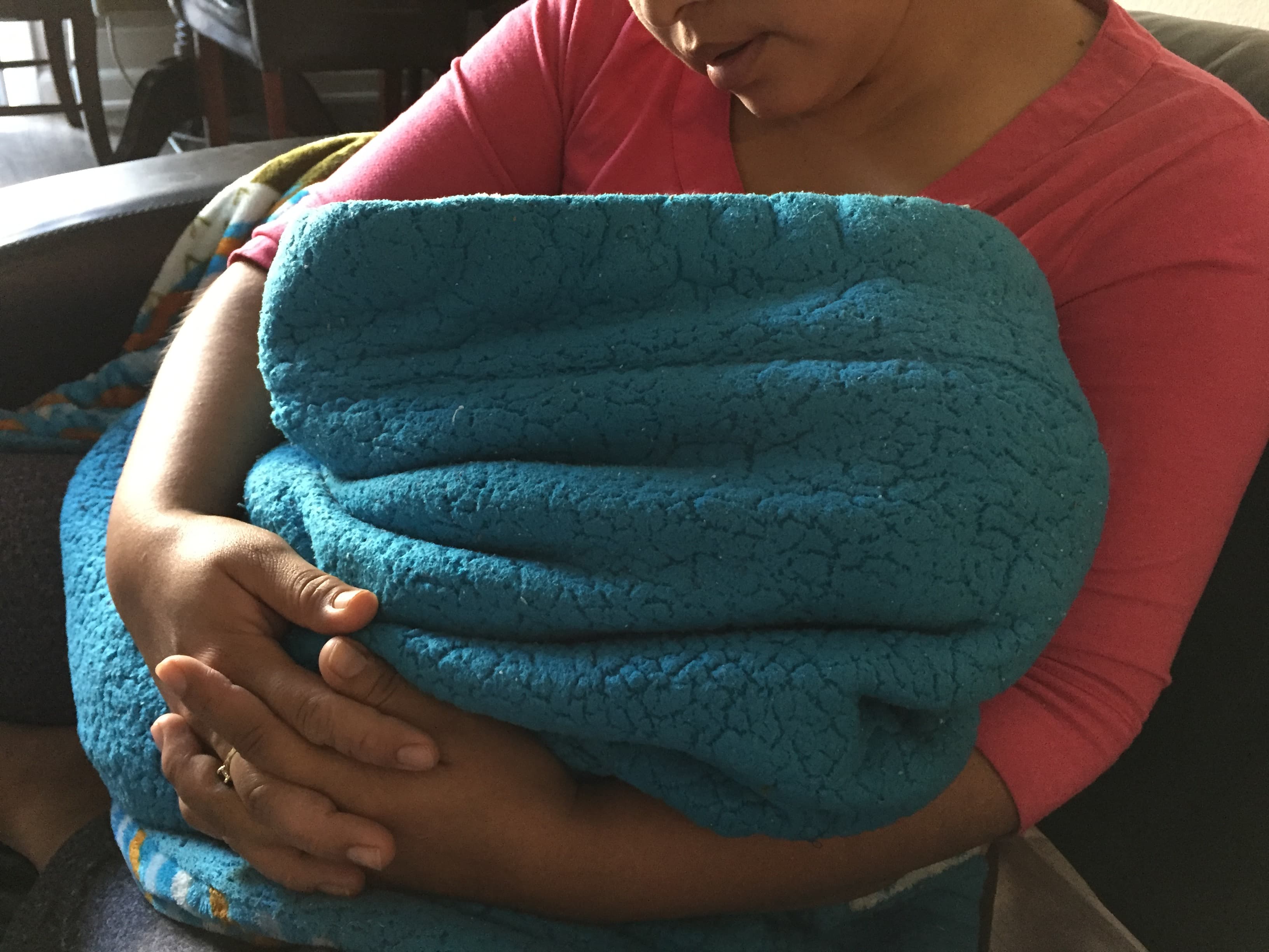 close up of woman holding child who is covered in blanket