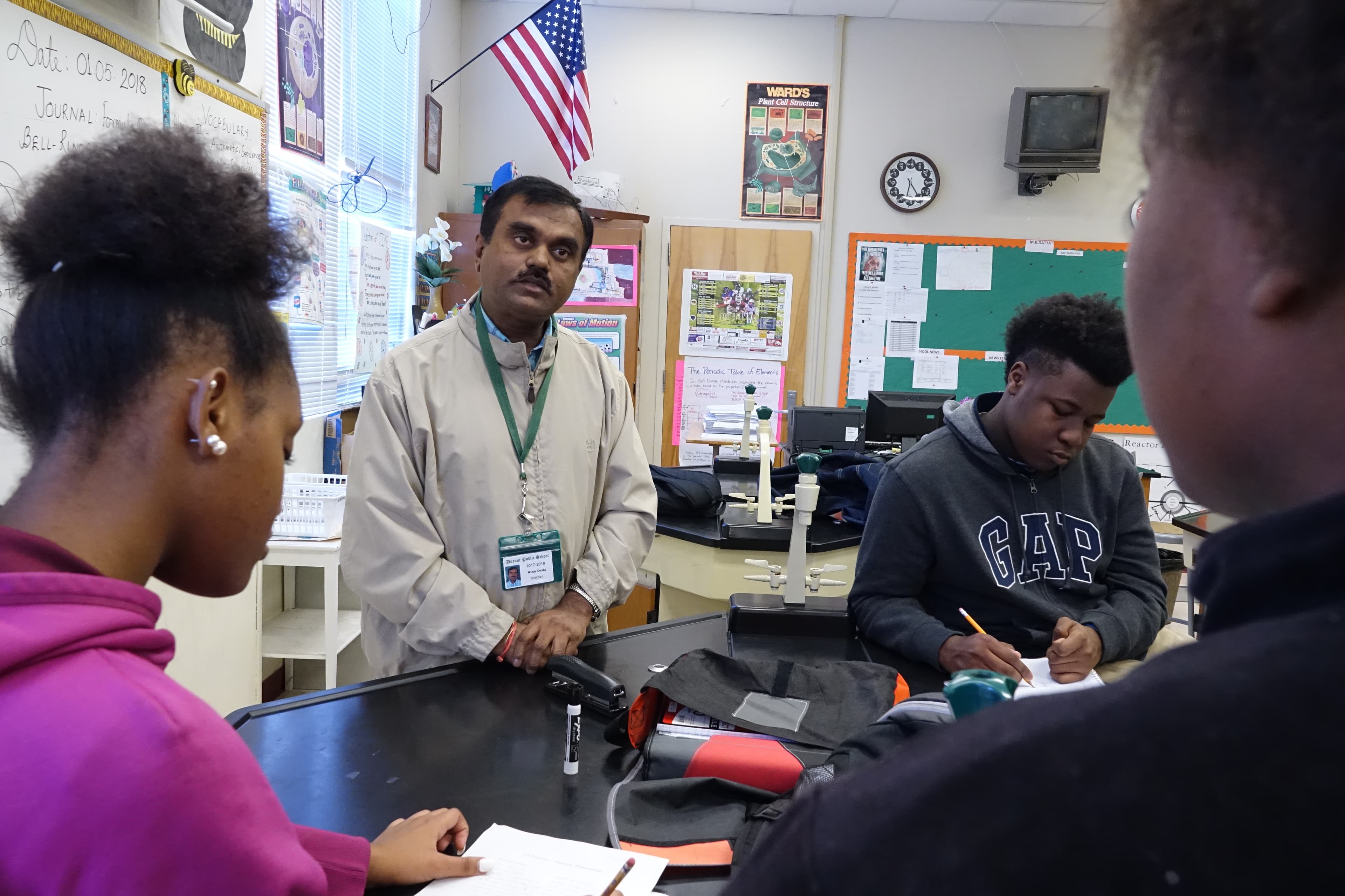 Man talking to students who sit around a round table