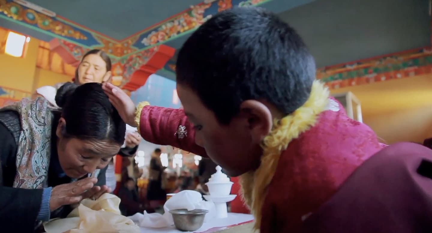 Padma Angdu blesses his followers from a cushioned throne.