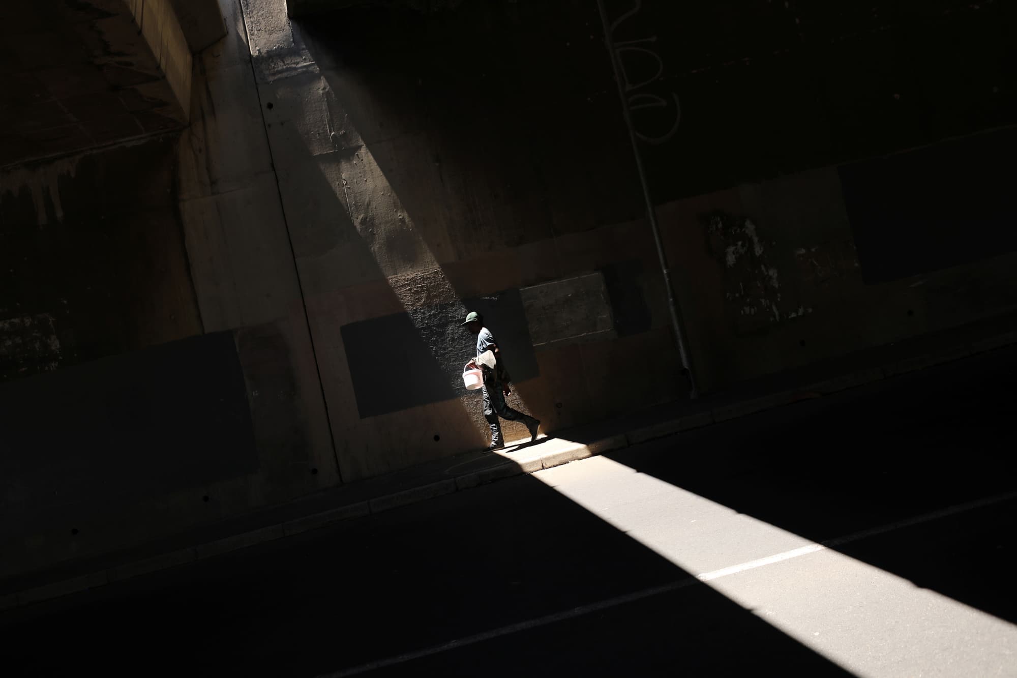 A man carries a bucket used to collect water from a small roadside spring in Cape Town, South Africa.