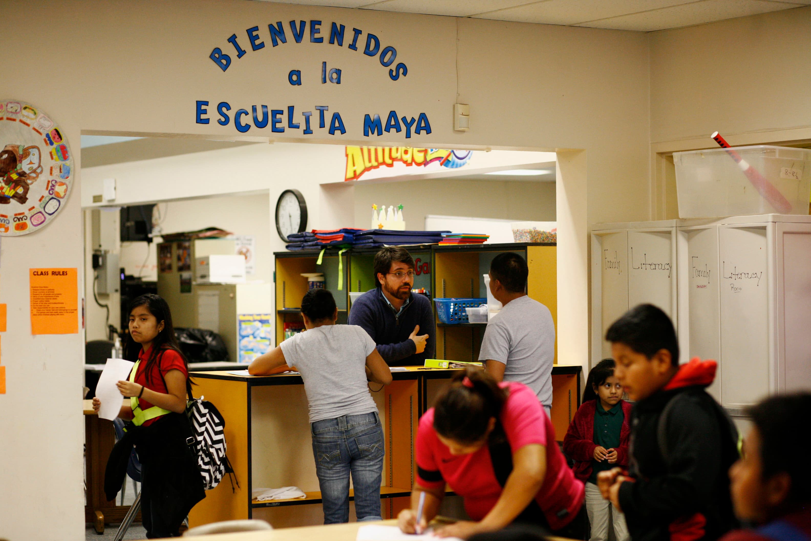 Man stands behind counter, talking to young people