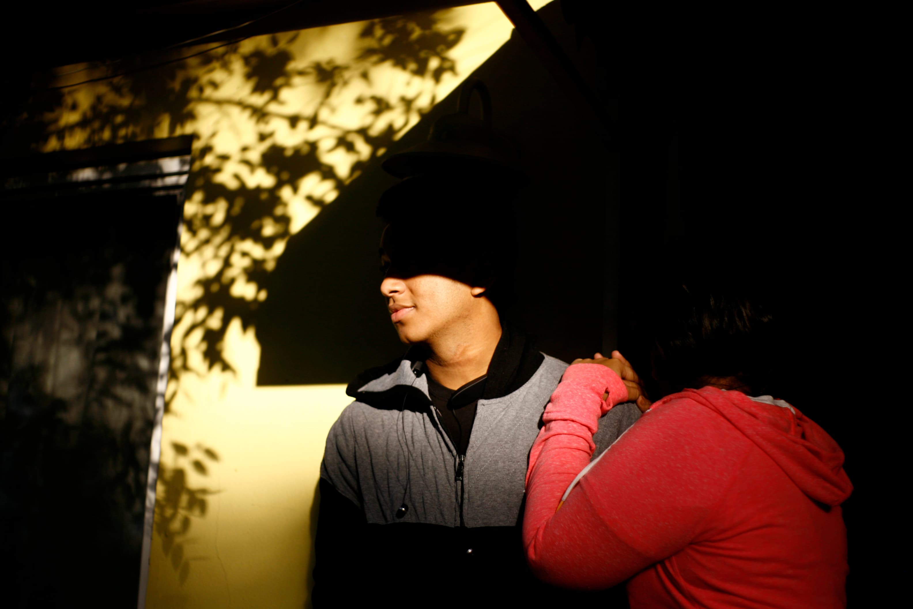 Young man and woman in shadows in front of building
