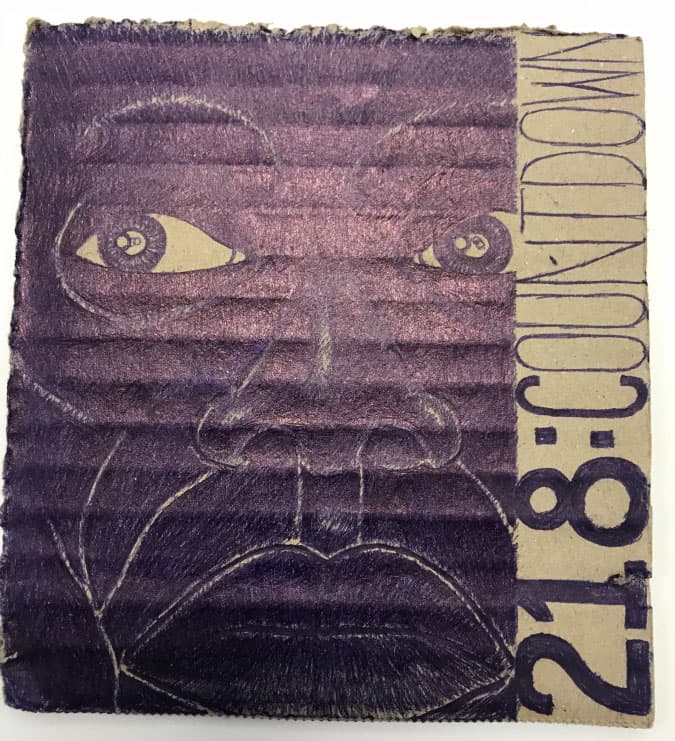 On a piece of cardboard, a cartoonist has a drawn a face next to the words 218: Countdown in blue innk