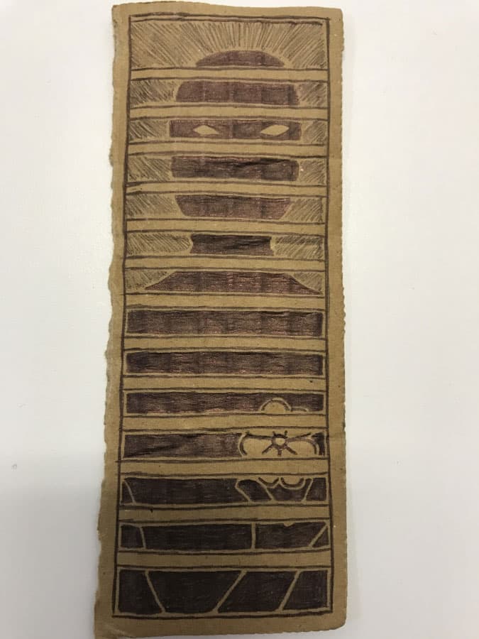 A piece of cardboard has a hand-drawn cartoon image of a silhouette staring between prison bars