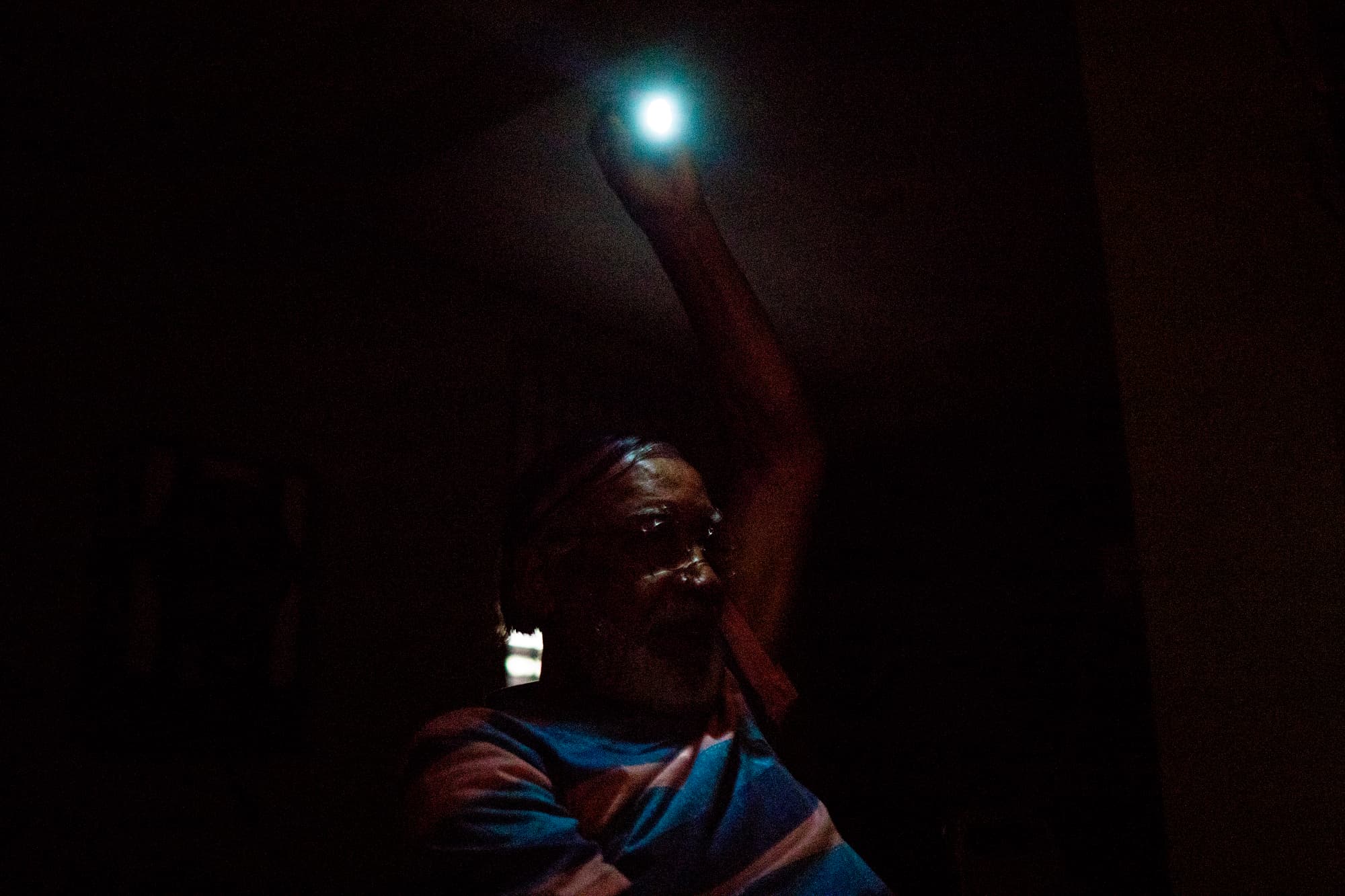 person hanging a lightbulb in a dark room
