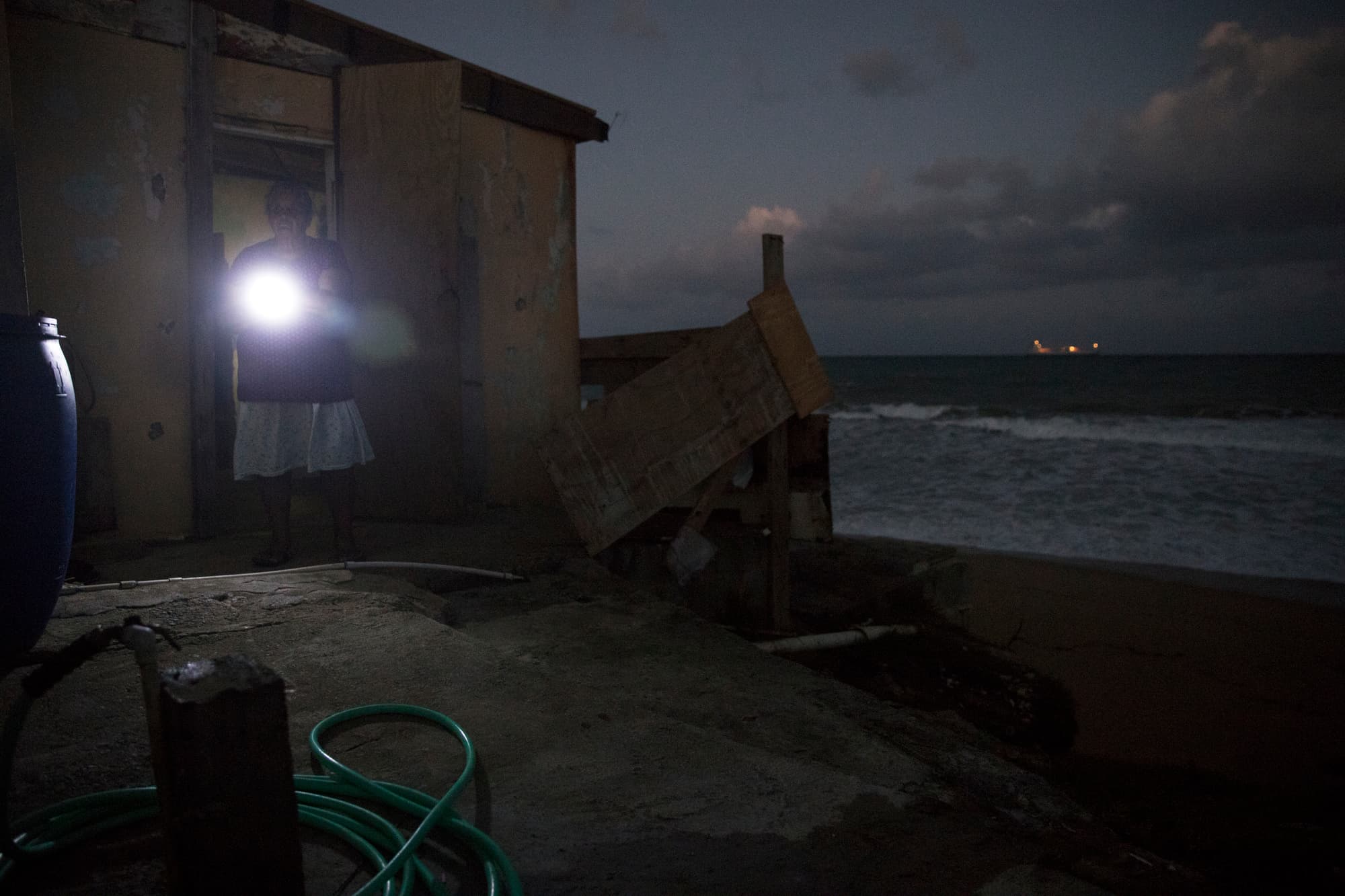 Irma Torres guides herself by flashlight at her home