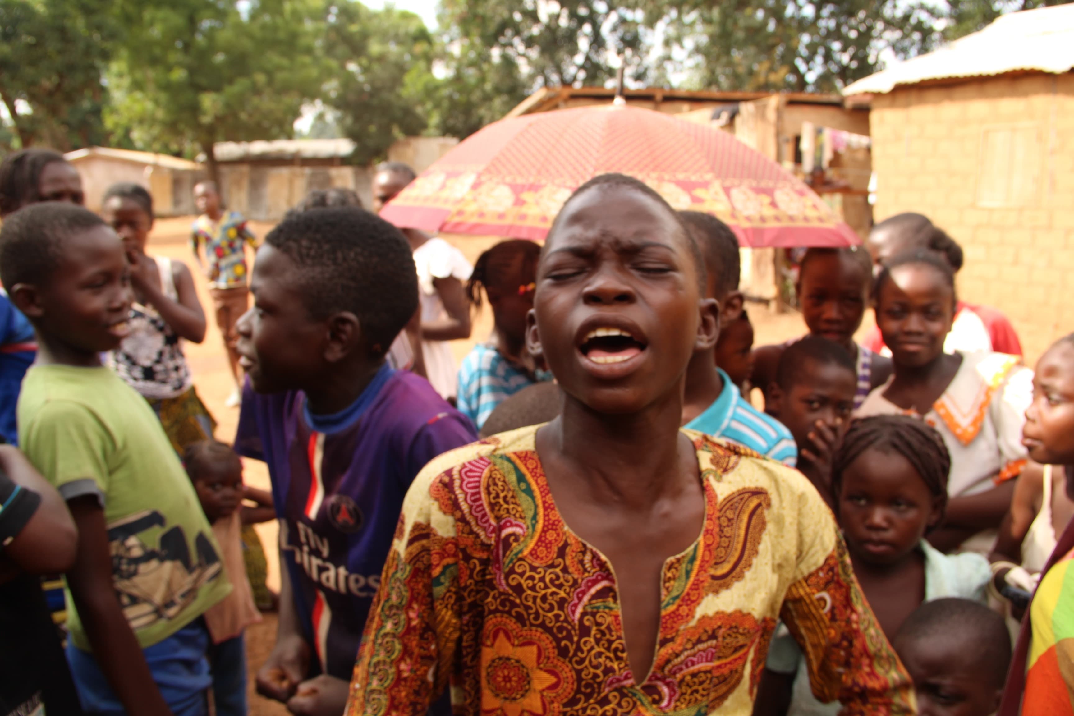 Fortuné pours his heart into singing a hymn outside of his home in the Miskine neighborhood in Bangui.