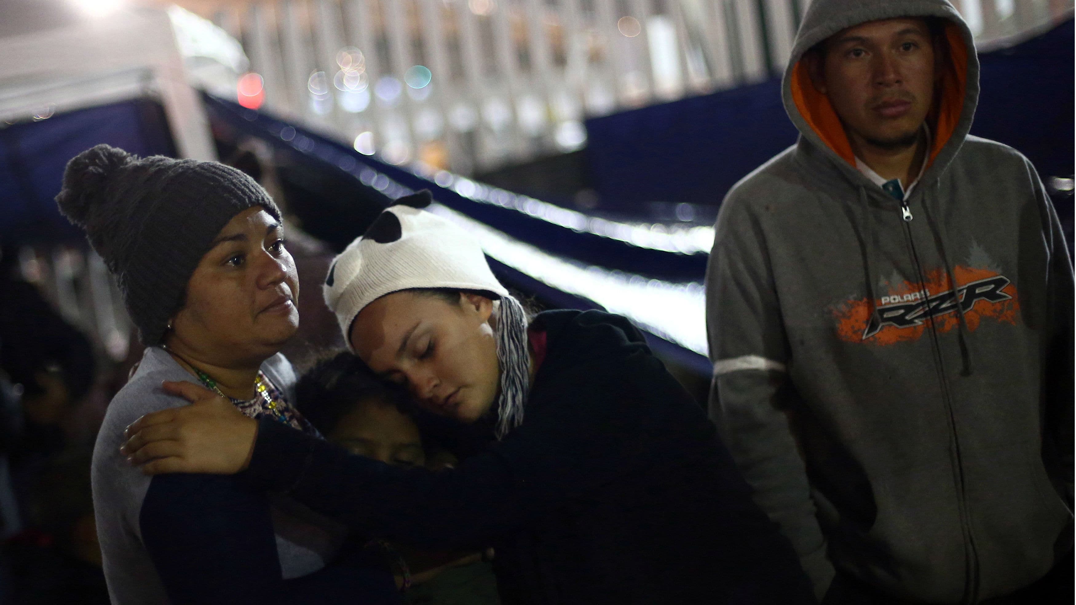 Three members of a caravan of migrants from Central America embrace and pray near the San Ysidro checkpoint after the first fellow migrants entered U.S. territory to seek asylum, at an improvised shelter in Tijuana, Mexico, on April 30, 2018.