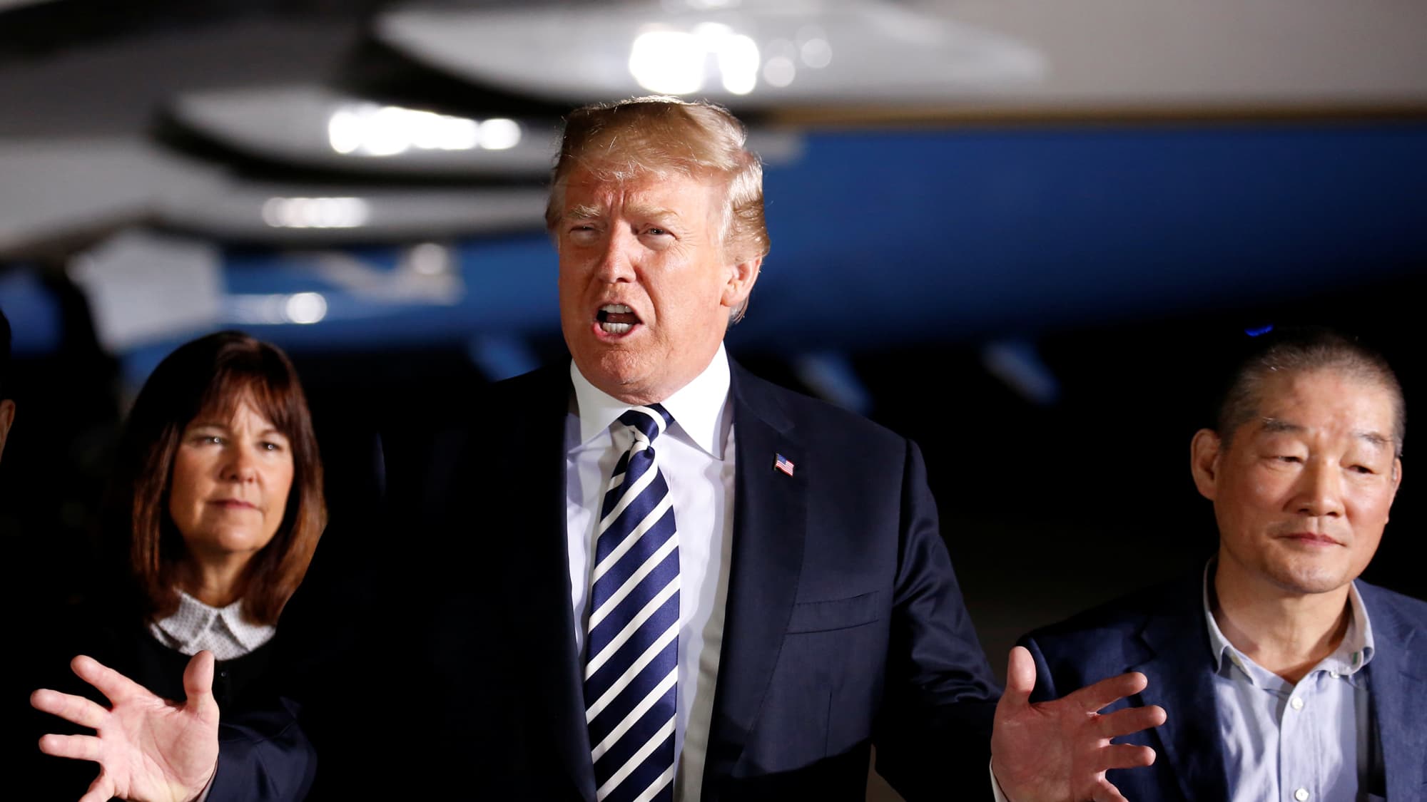 President Donald Trump talks to the media next with his hands outstretched on the tarmac at Joint Base Andrews, Maryland.