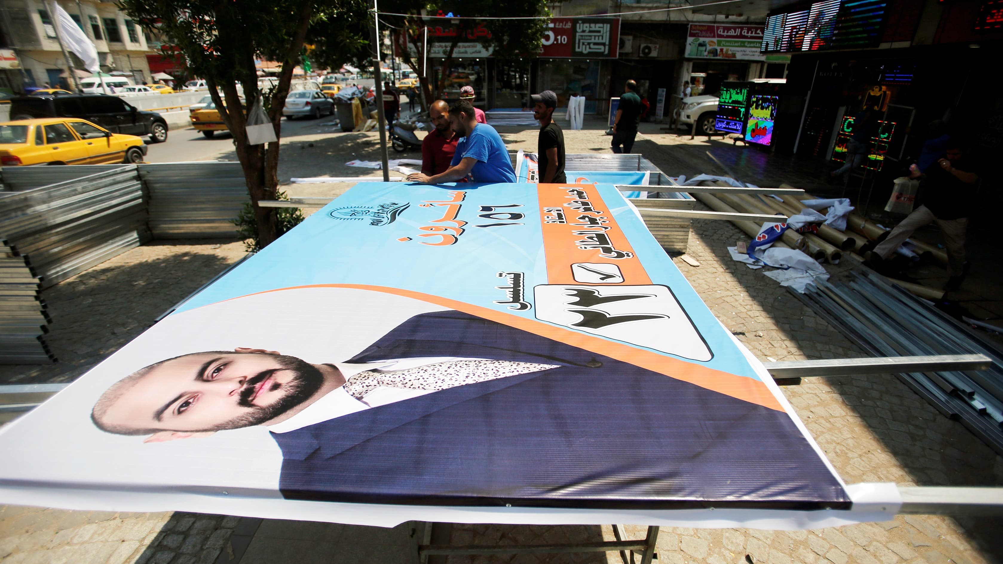 Iraqi men work on the campaign posters of candidates ahead of May's parliamentary election, in Baghdad, Iraq, April 14, 2018.