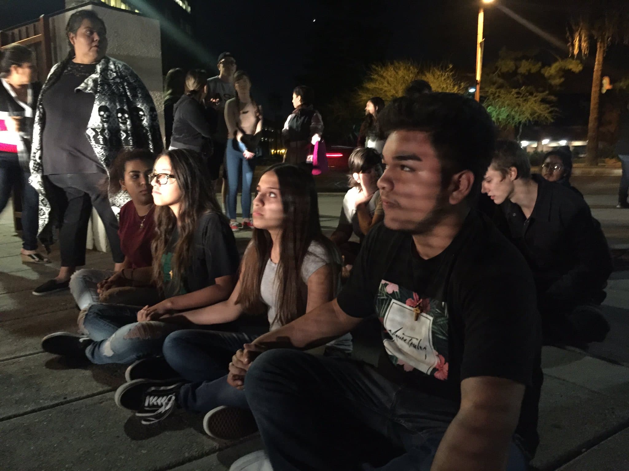 People sitting on pavement holding hands