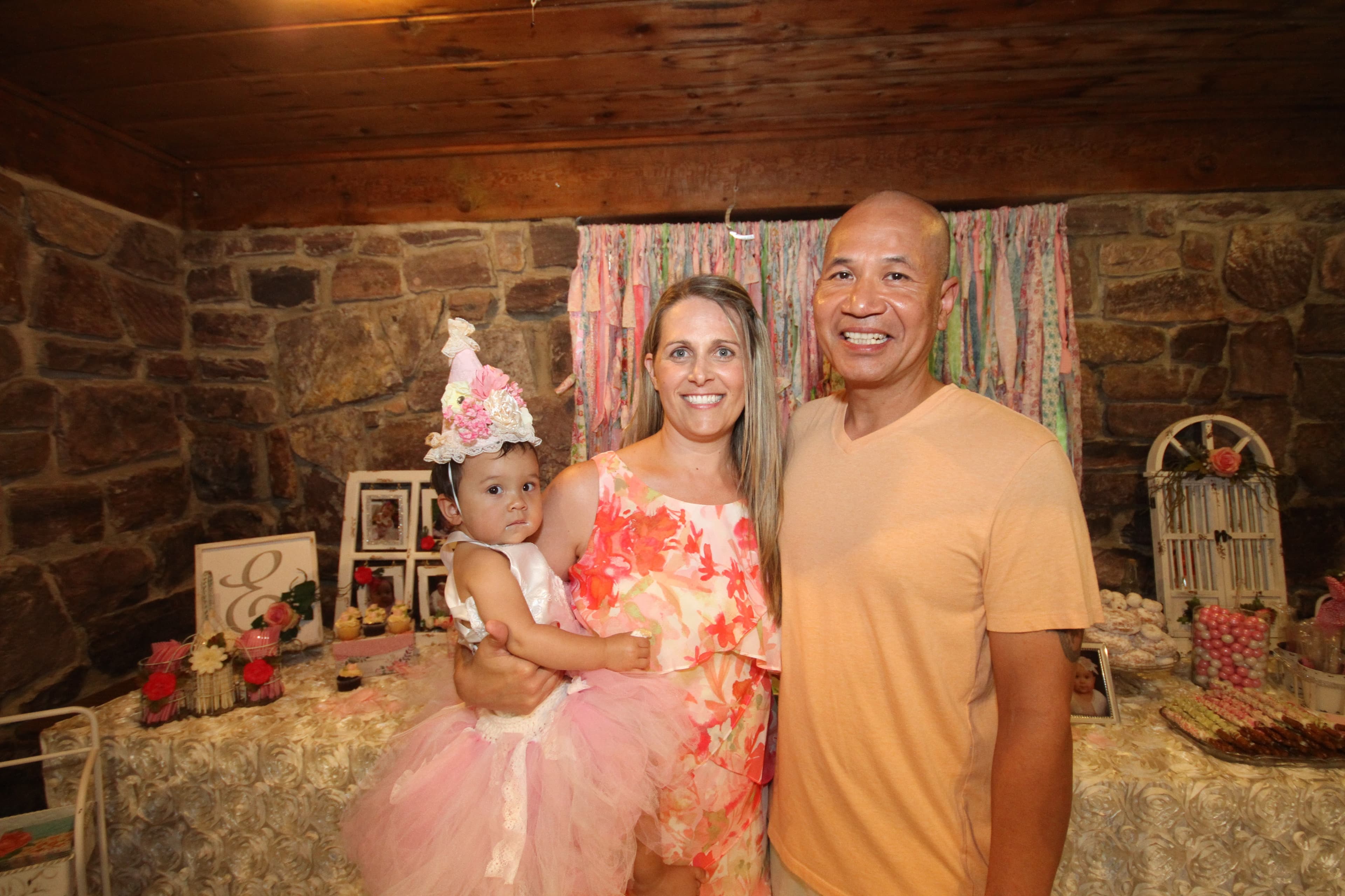 Woman and man with baby in front of table decorated for child's birthday