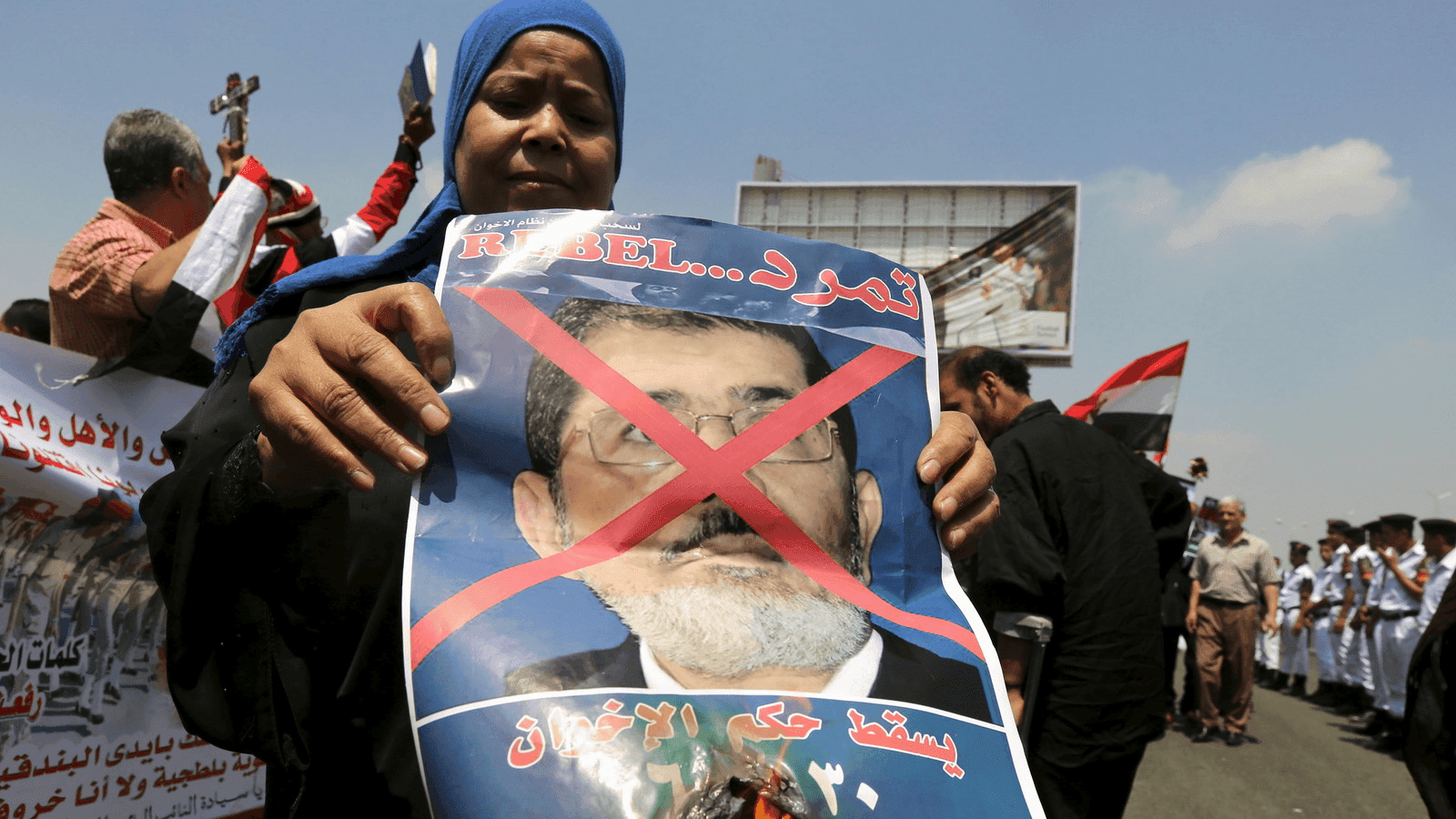 A woman burns a portrait of ousted President Mohamed Mursi at the funeral of Egyptian public prosecutor Hisham Barakat, on the second anniversary of the June 30 protests, in Cairo, Egypt, June 30, 2015.