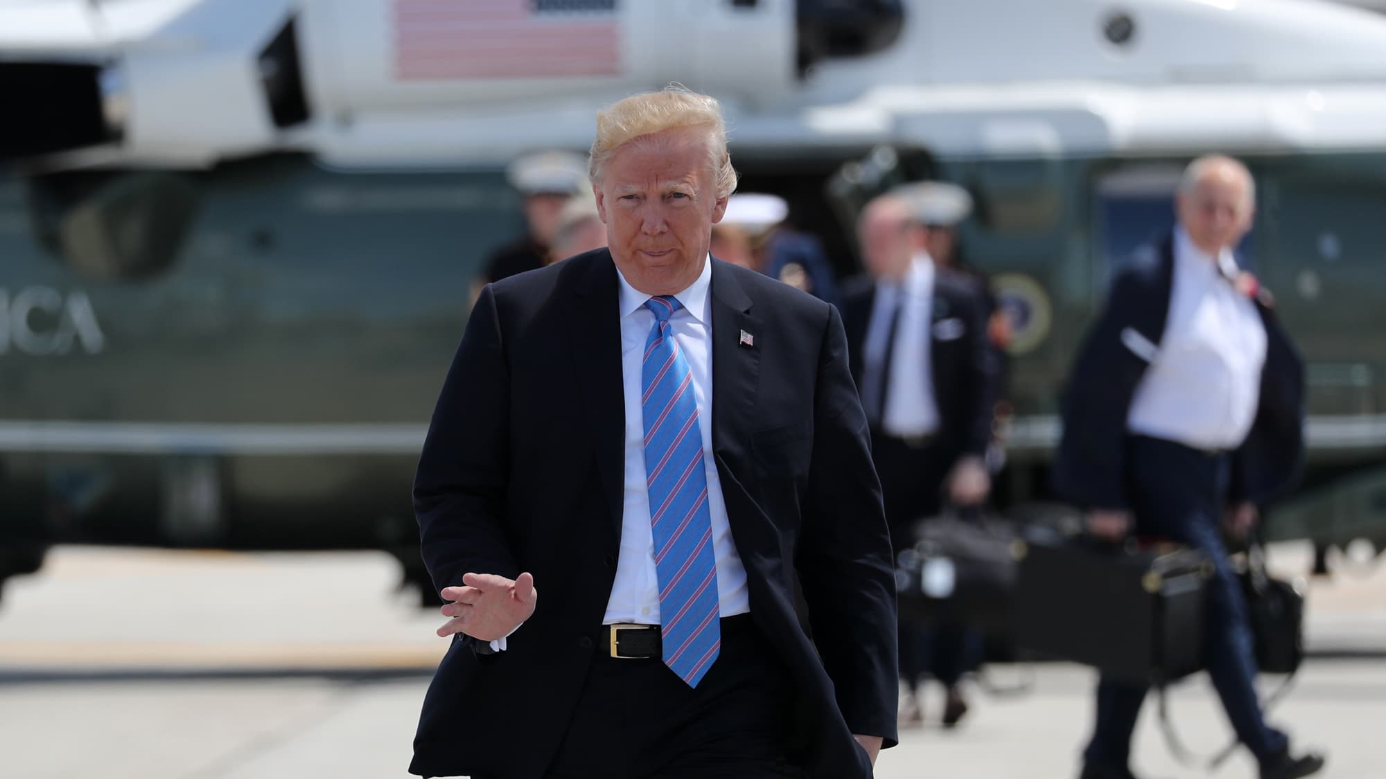 US President Donald Trump, wearing a suit and blue-stripped tie, waves as he arrives to board Air Force One.