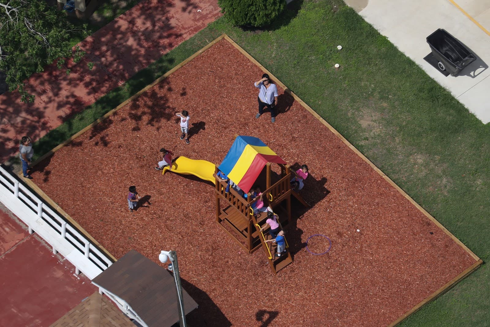 Migrant children outside playing on a playground at Casa Combes, a shelter for migrant kids in Harlingen, Texas. Photographed on June 23, 2018.