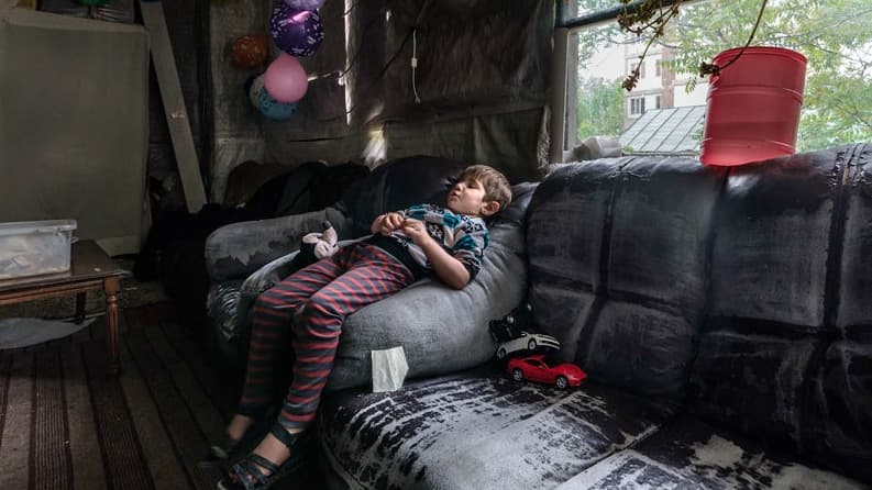 A young girl sits on a couch.