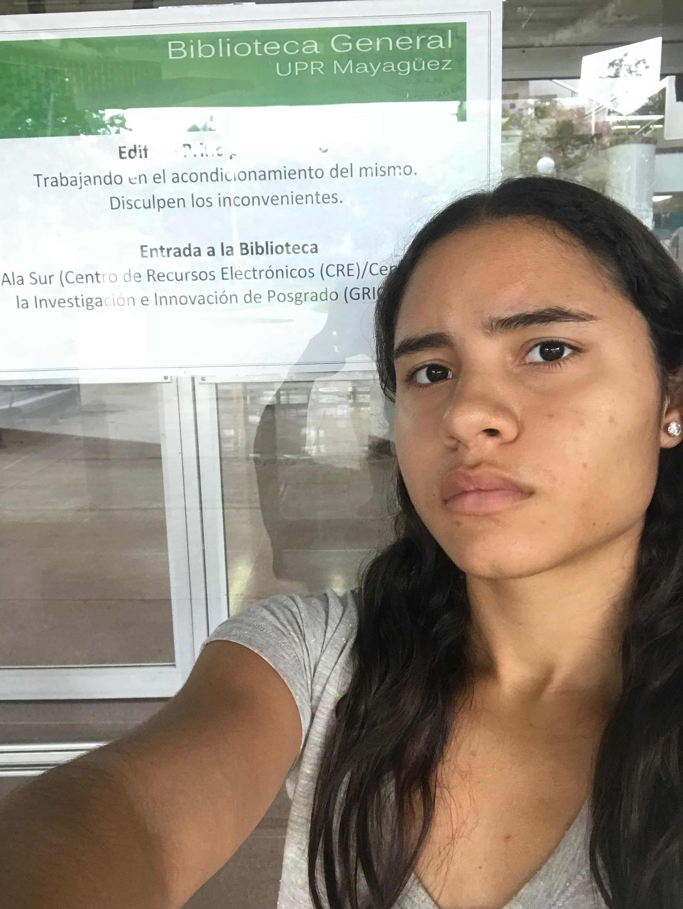 A woman takes a selfie in front of a sign.