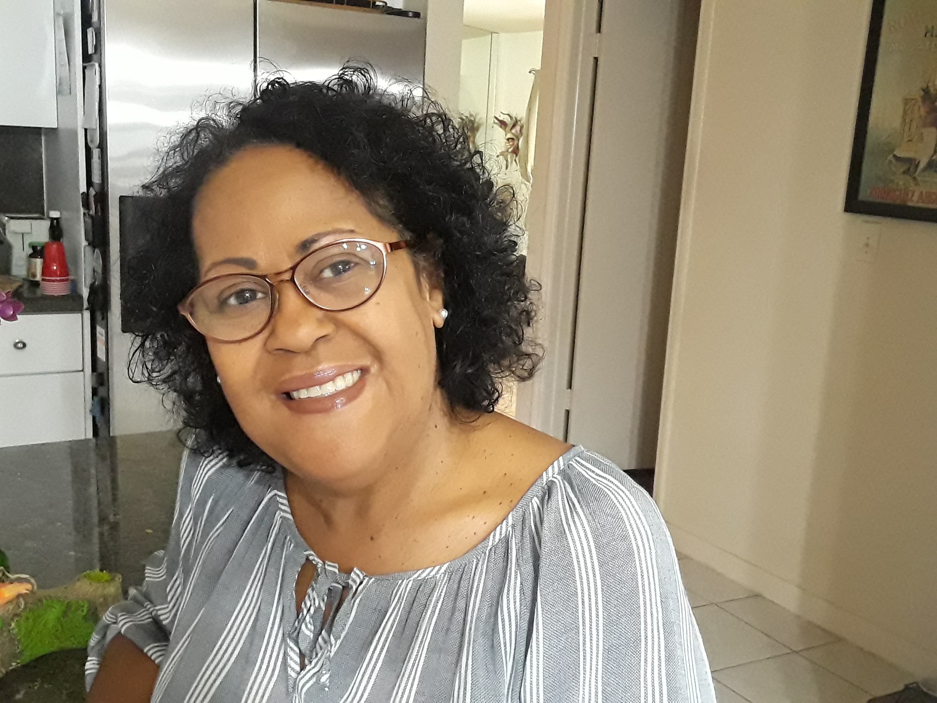 Woman in kitchen, smiling at camera