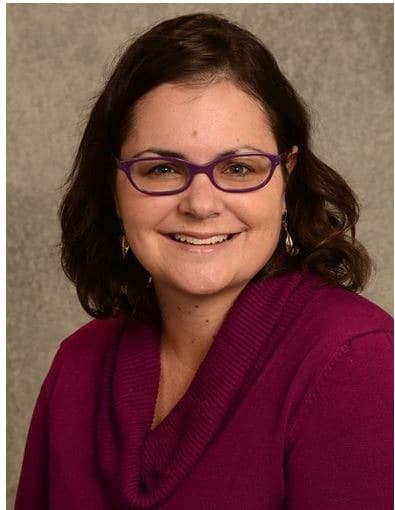 Portrait of woman against grey background, smiling for camera