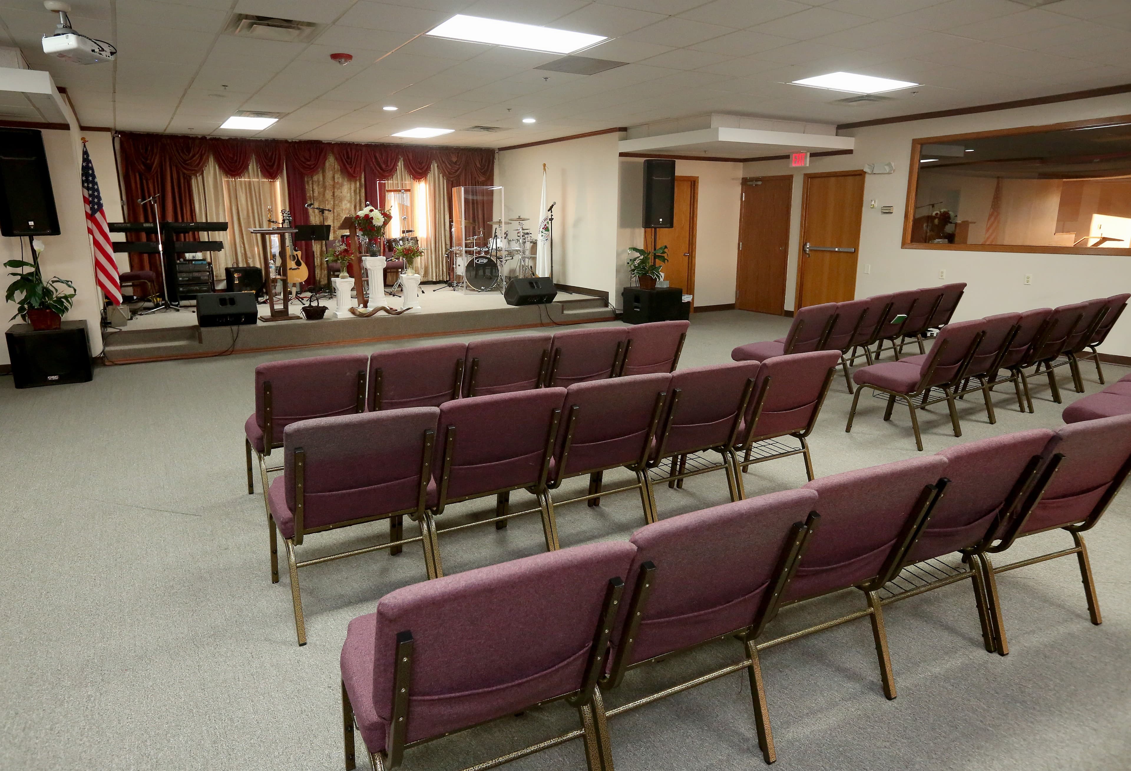 Inside of small church, with red pews and altar at front