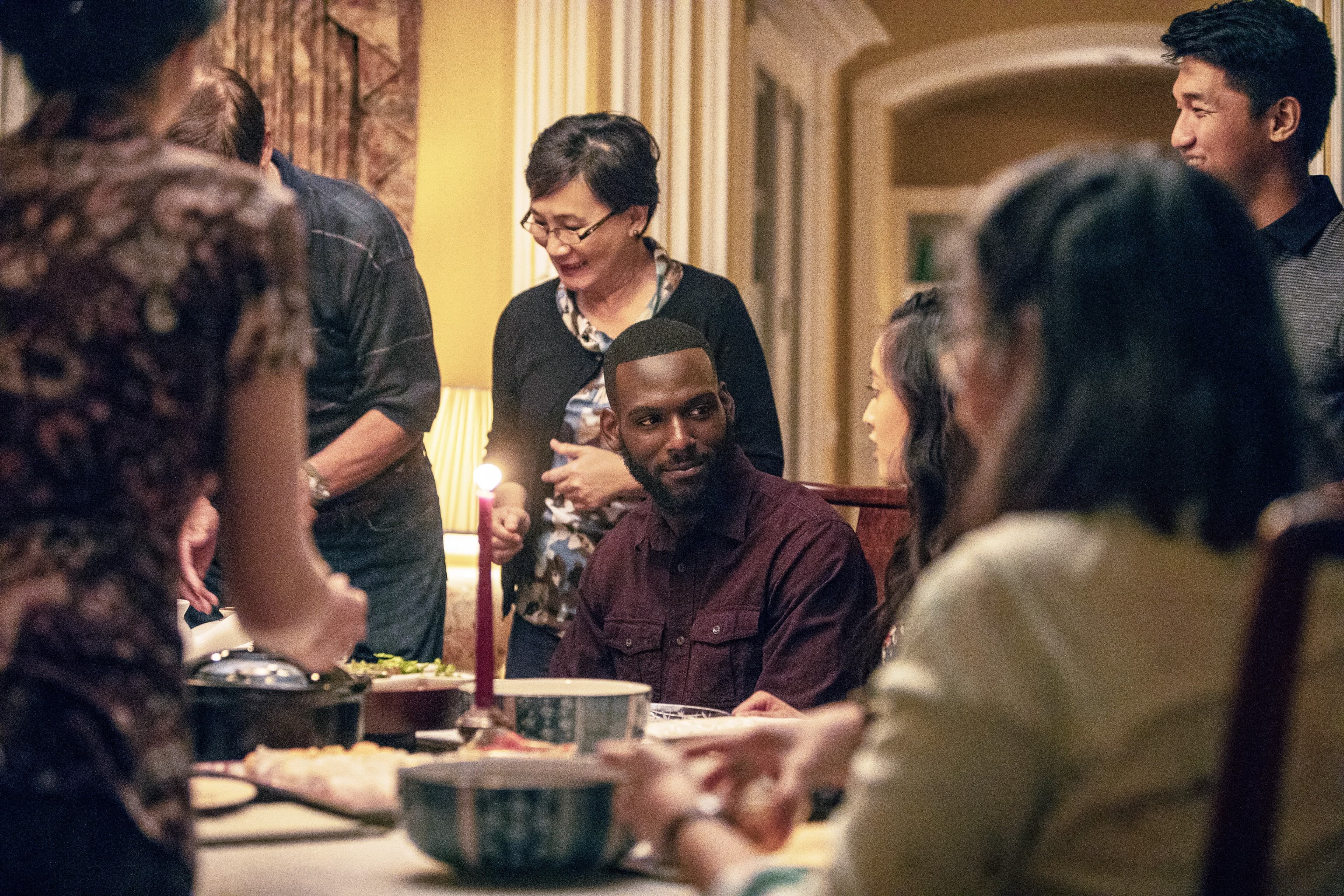 Man at dinner table, surrounded by people