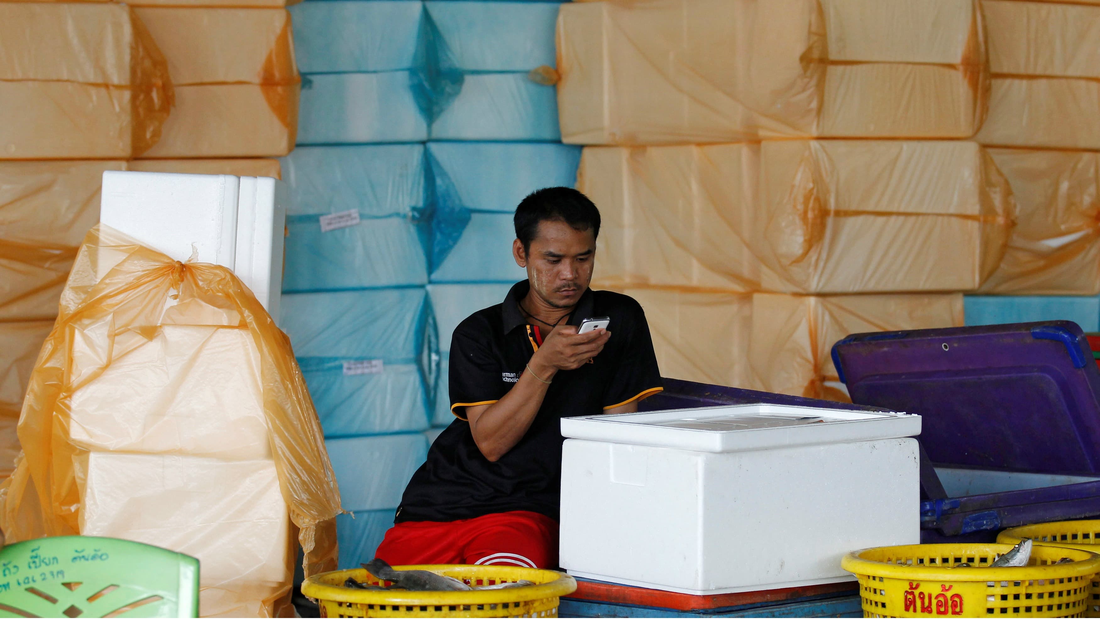 A migrant worker from Myanmar looks at his cellphone at a wholesale market for shrimp and other seafood in Mahachai, in Samut Sakhon province, Thailand, July 4, 2017.