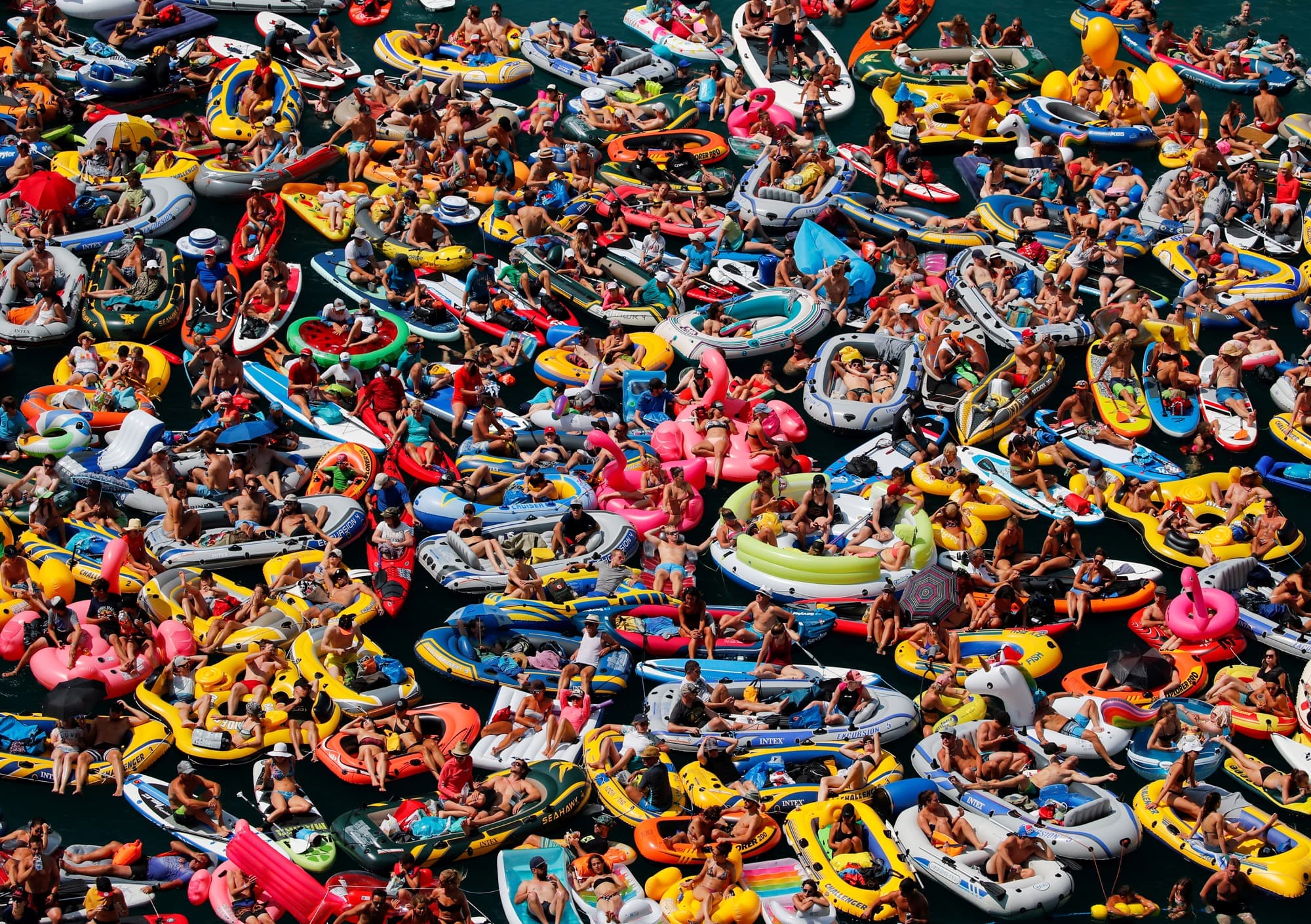 People on inflatable boats enjoy the sun as they watch the Red Bull Cliff Diving competition on Lake Lucerne in Sisikon, Switzerland.