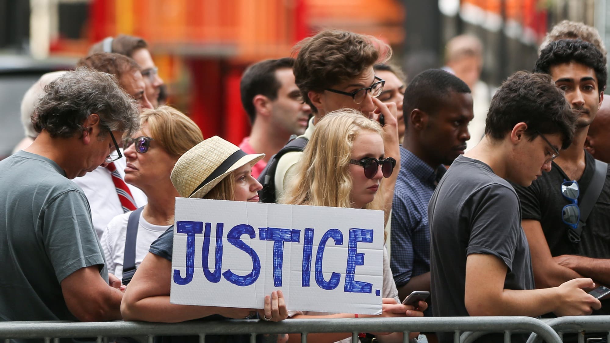 A woman hold a placard as she waits President Donald Trump's former lawyer, Michael Cohen, to leave the Daniel Patrick Moynihan United States Court House in New York City, August 21, 2018.