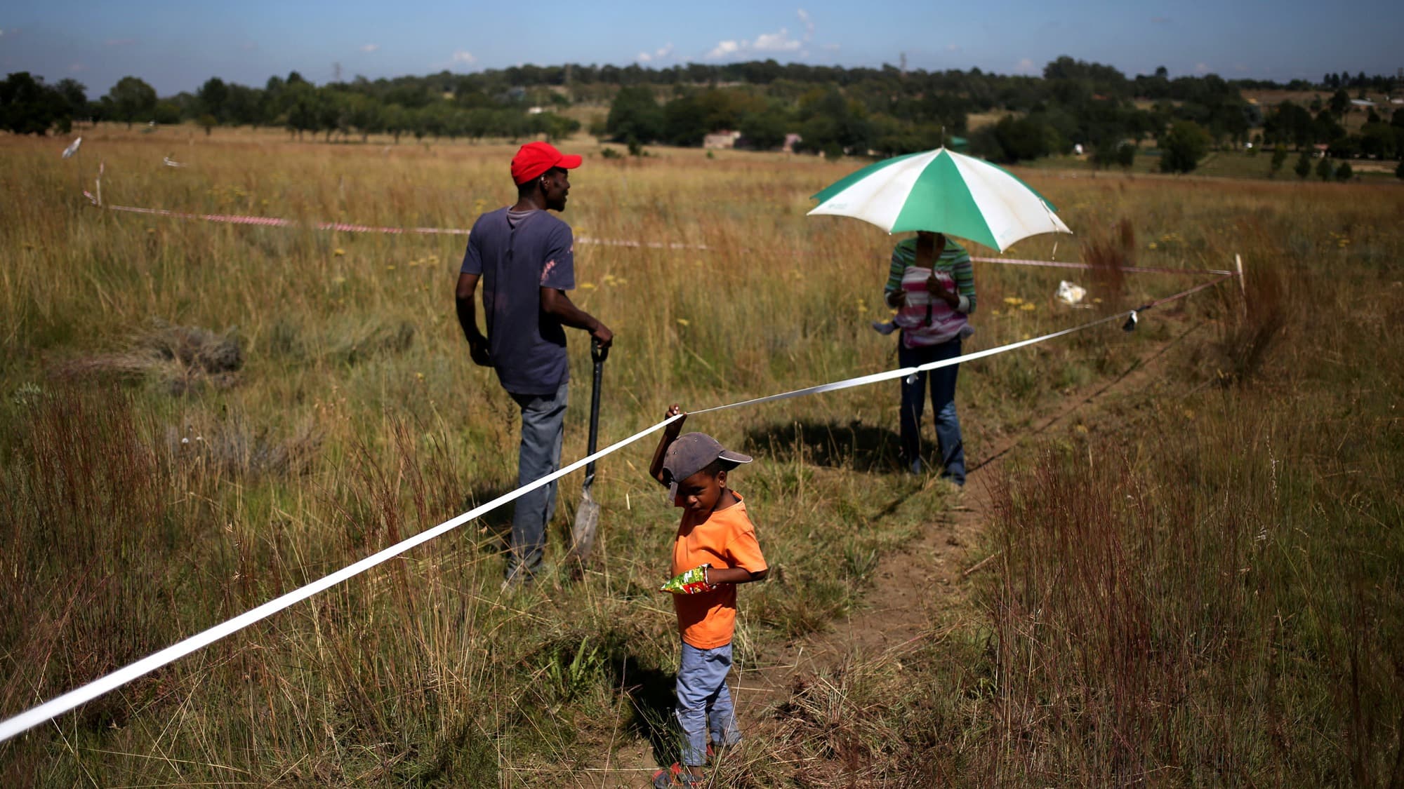 A couple and their child are seen on vacant land marked with tape in Olievenhoutbosch near Centurion, South Africa.