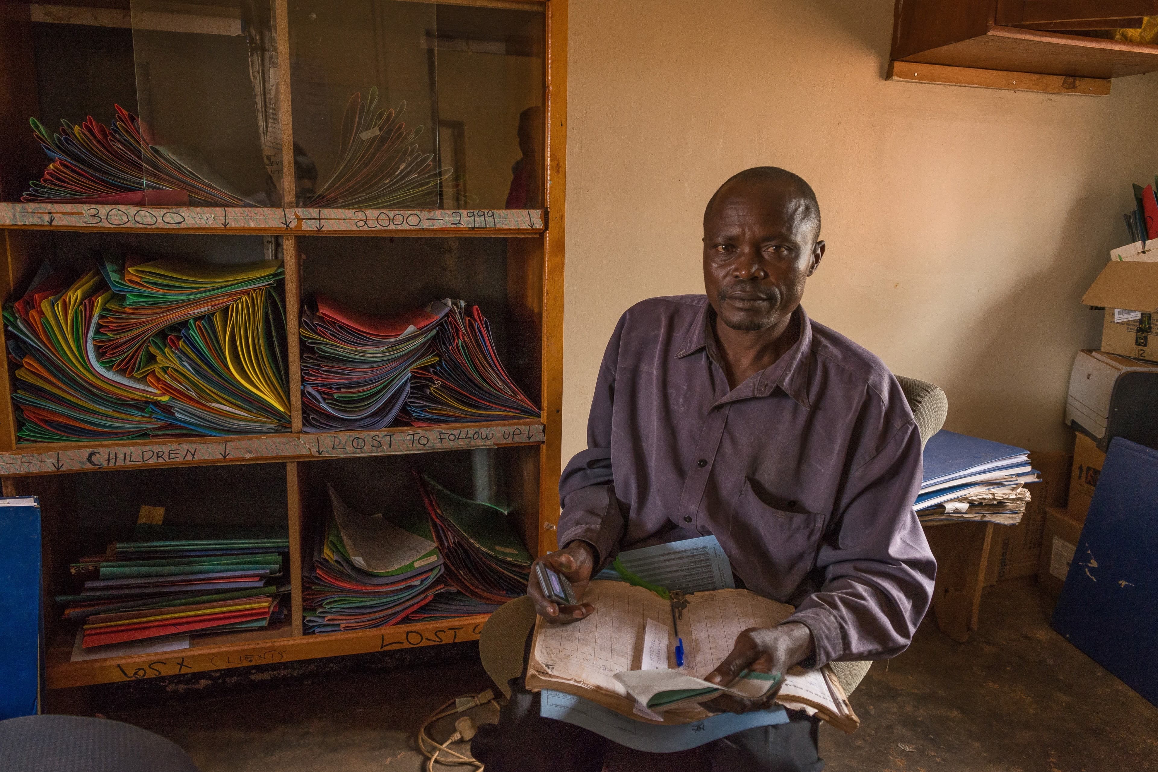 a clinic worker sits in front of patient records stored in old folders