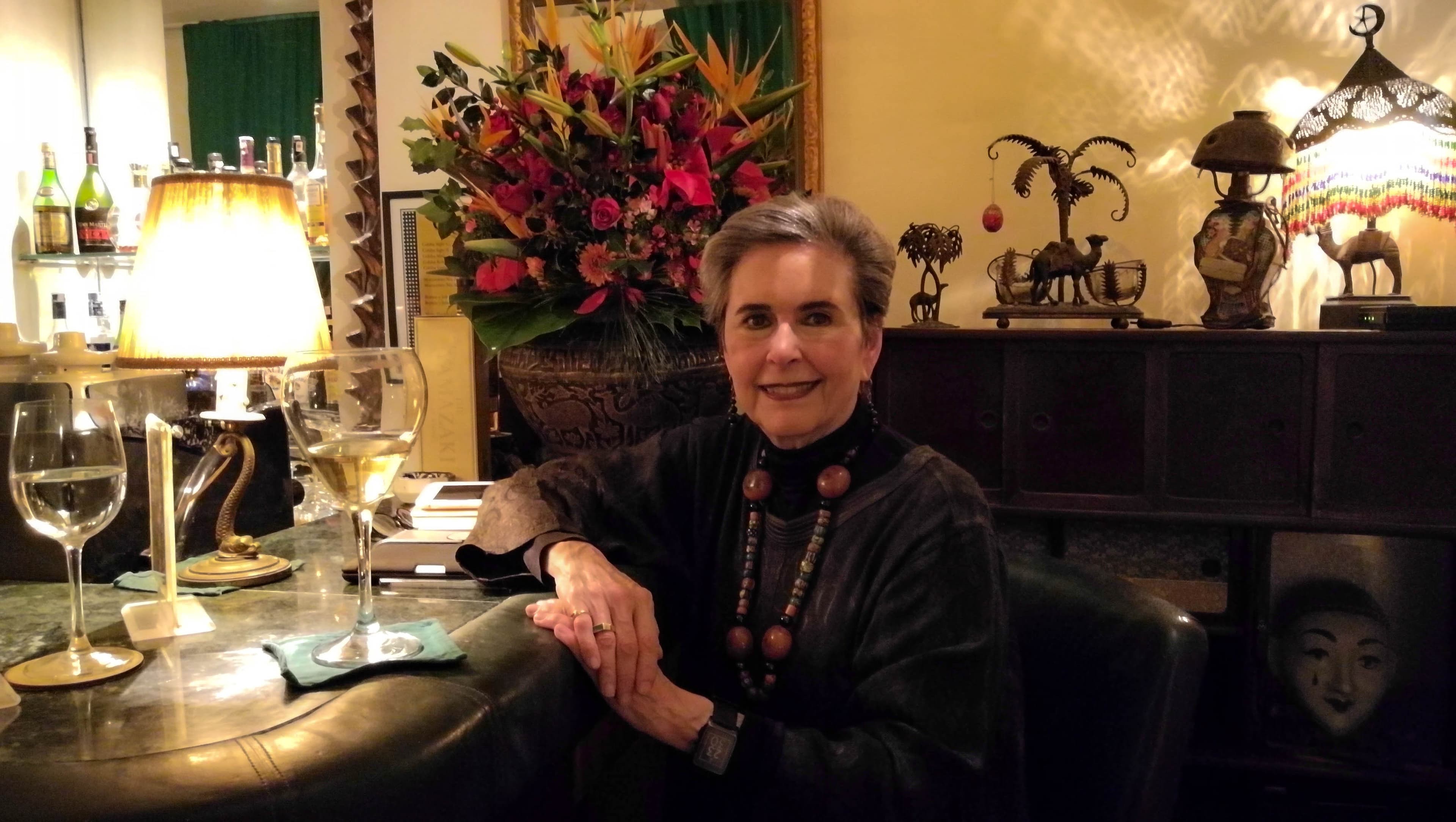 Kathy Kriger sitting at a bar next to a glass of wine