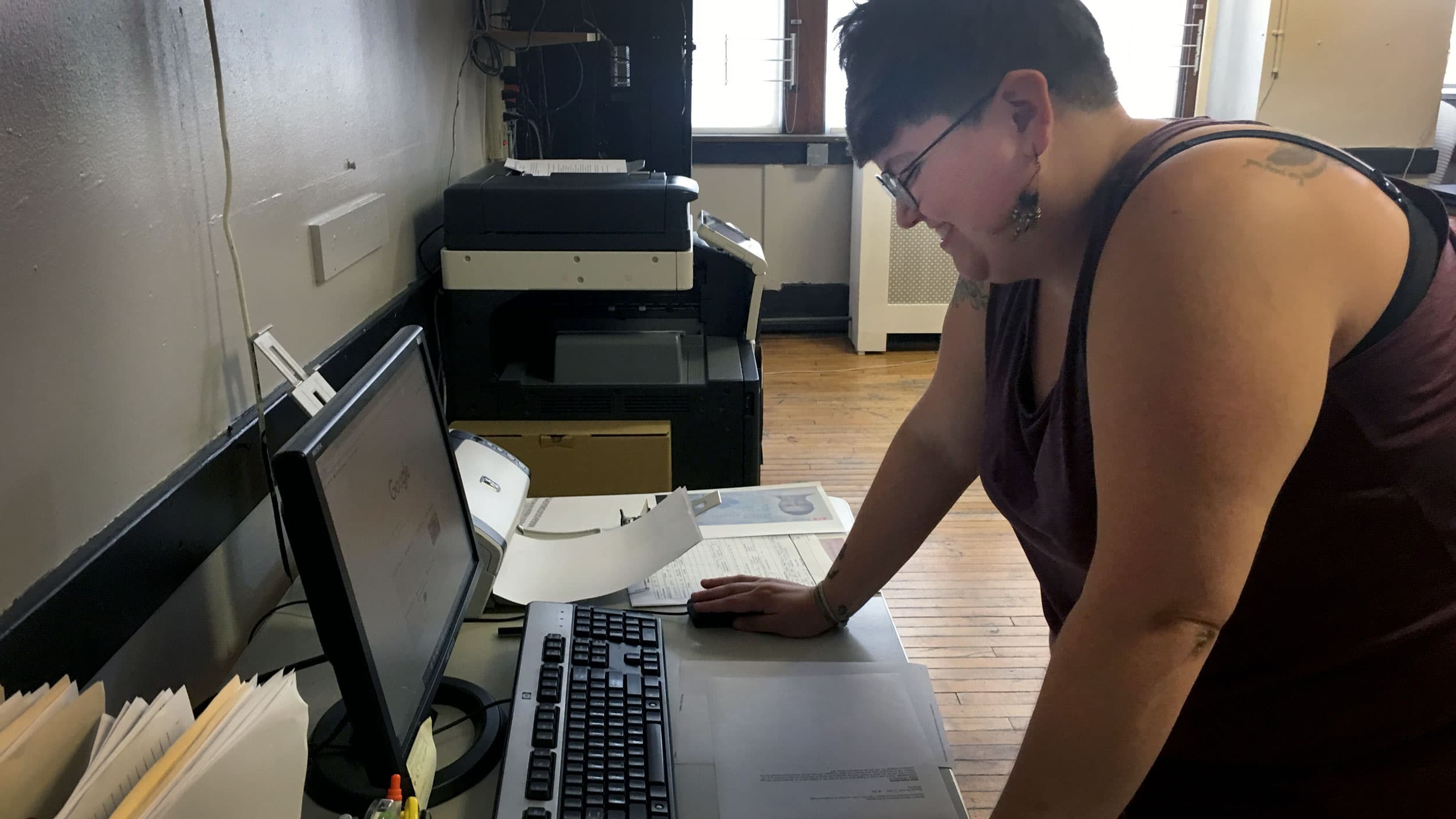 A woman leans over a computer