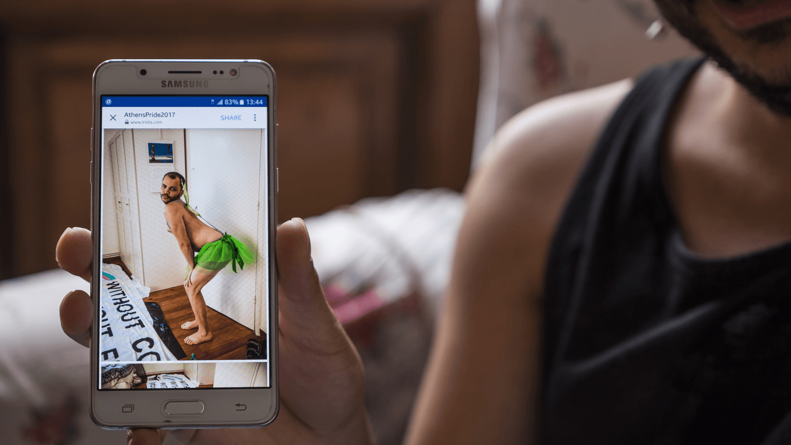 Lawrence Alatrash, 25, a non-binary gay Syrian refugee, shows a photo of himself on his mobile phone dressed up in a green tutu for last year's gay pride parade in downtown Athens, Greece.  