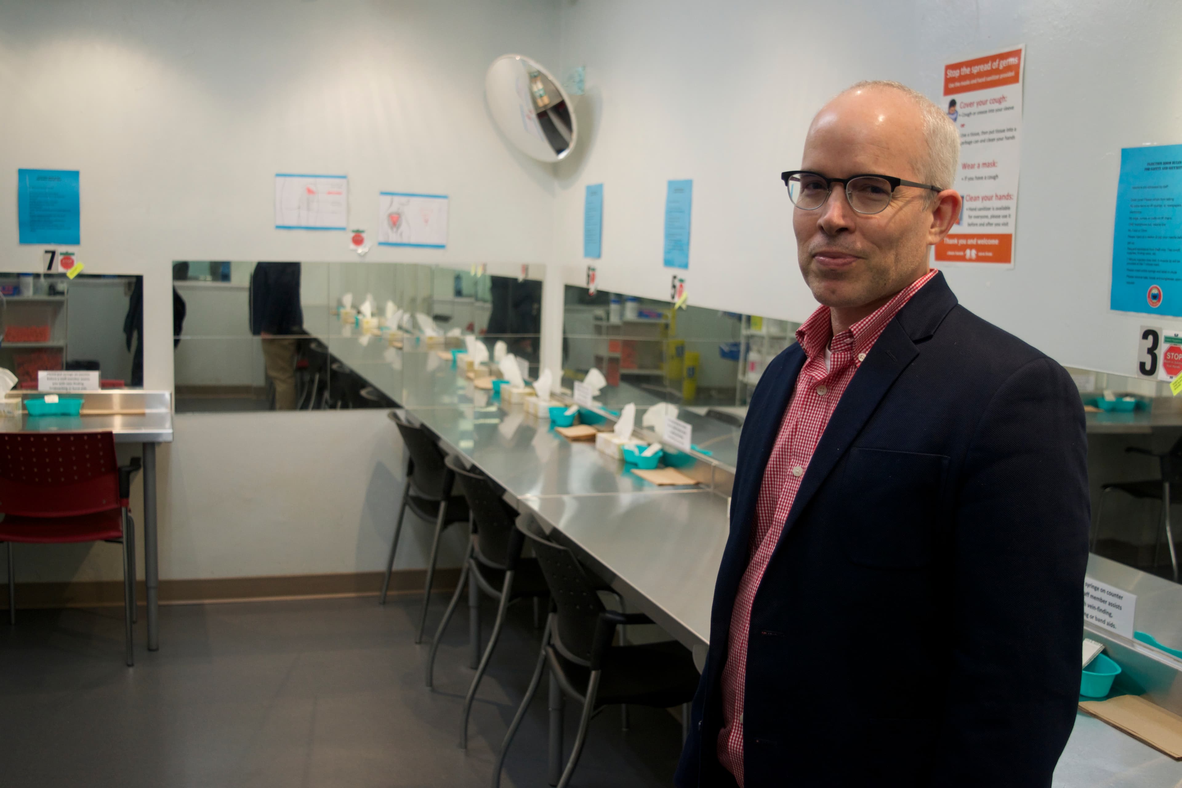 a man with glasses and a suit standing in a clinic