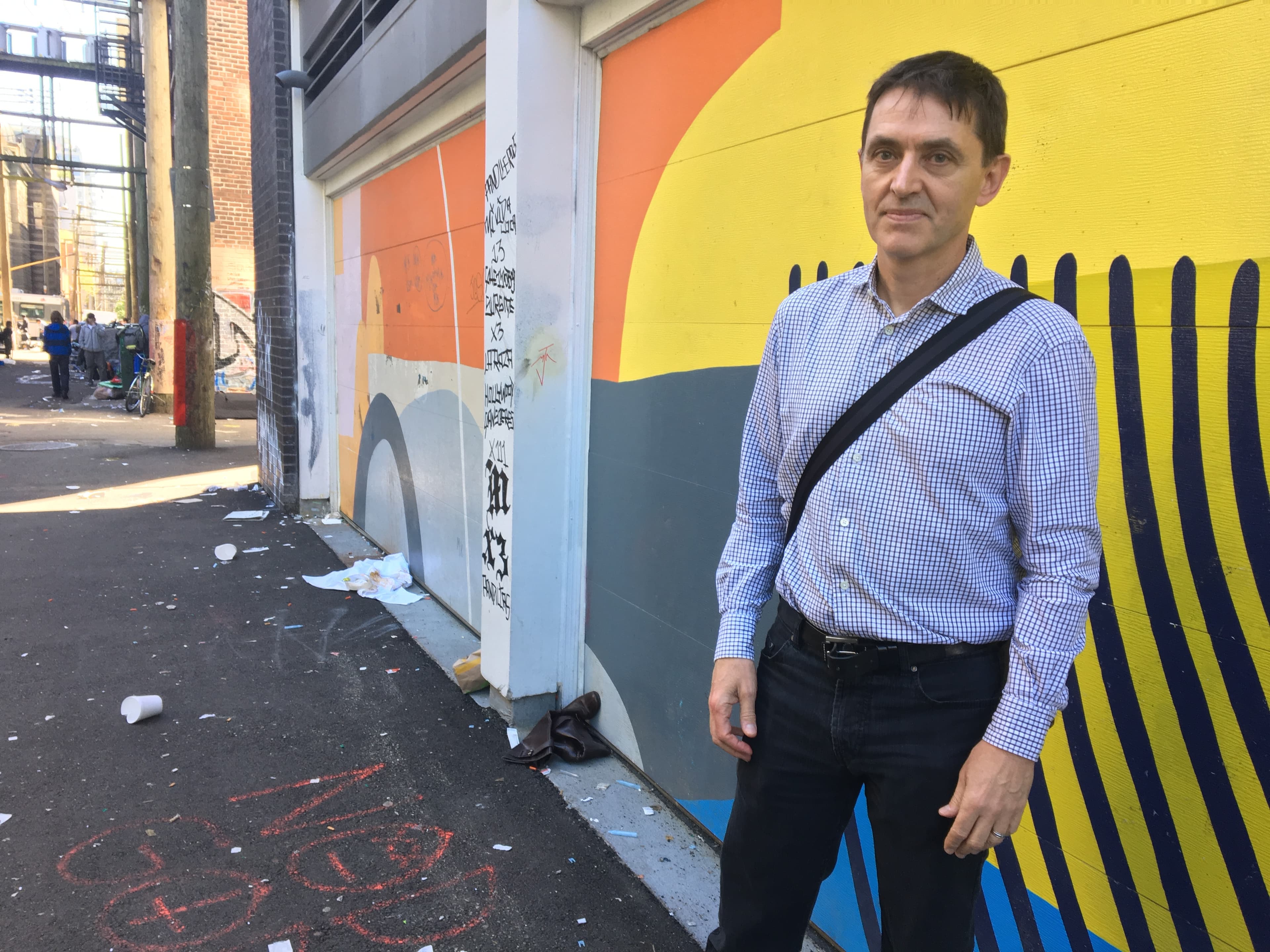 A man stands in a colorful alley