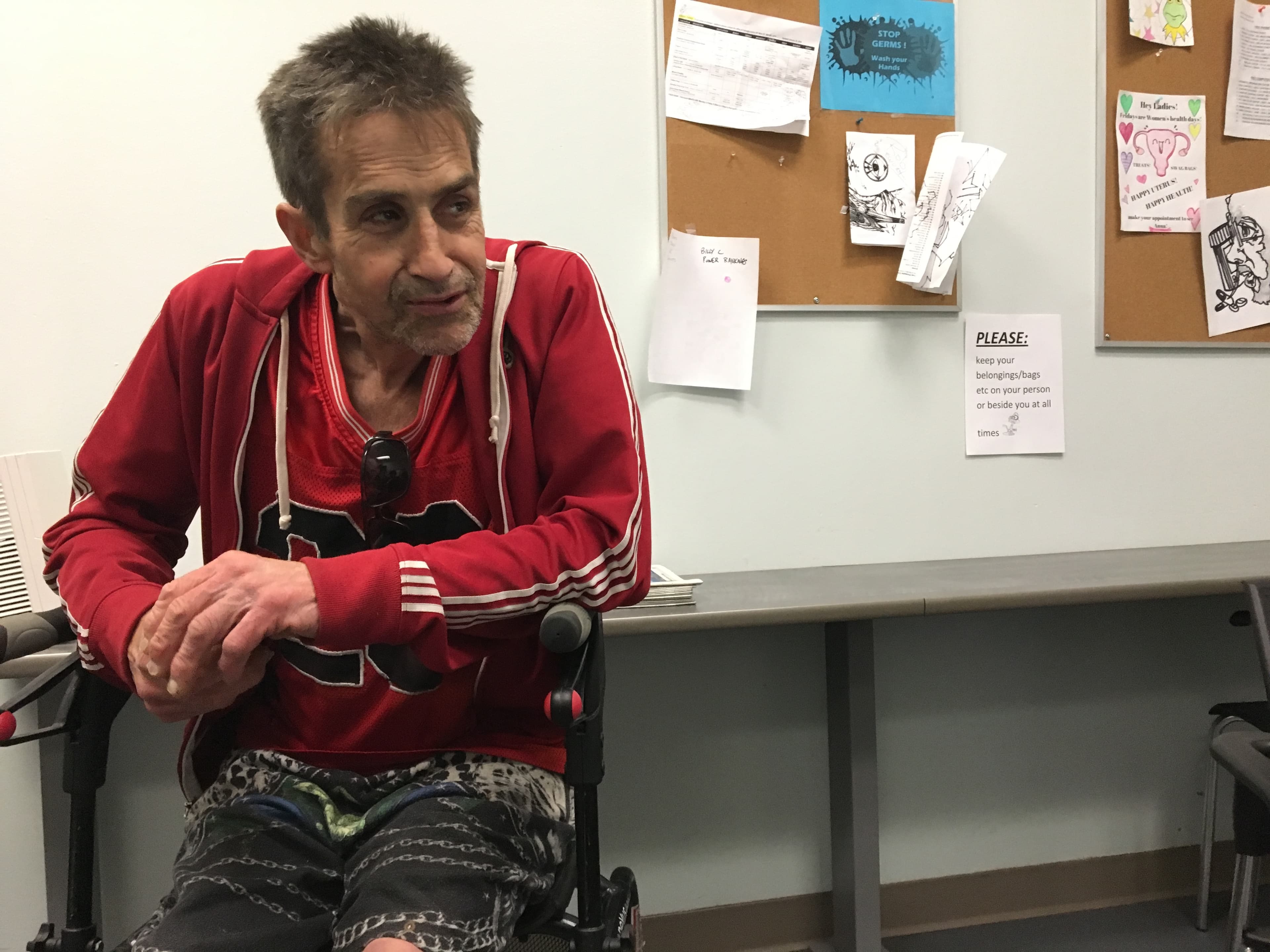 A man with a red sweatshirt sits in a clinic