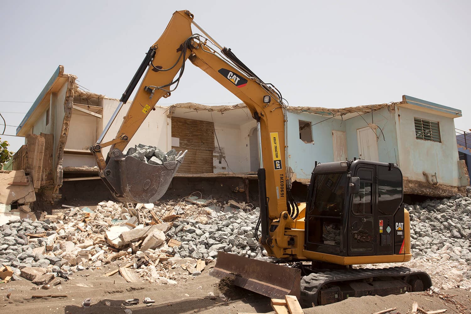 an excavator truck in front of the rubble of e building