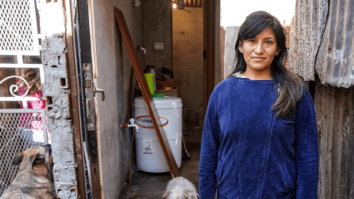 a woman in buenos aires stands in front of her informal home