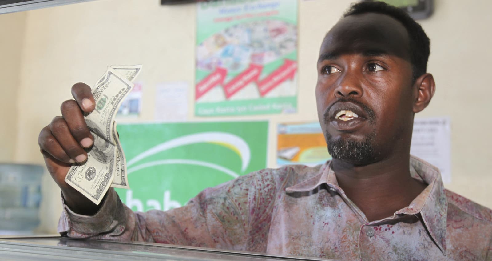 A customer receives US notes from a teller at the Dahabshill money transfer office in Mogadishu, Somalia, Feb. 16, 2015.