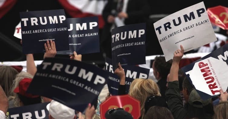 Supporters of President Donald Trump wave campaign signs.