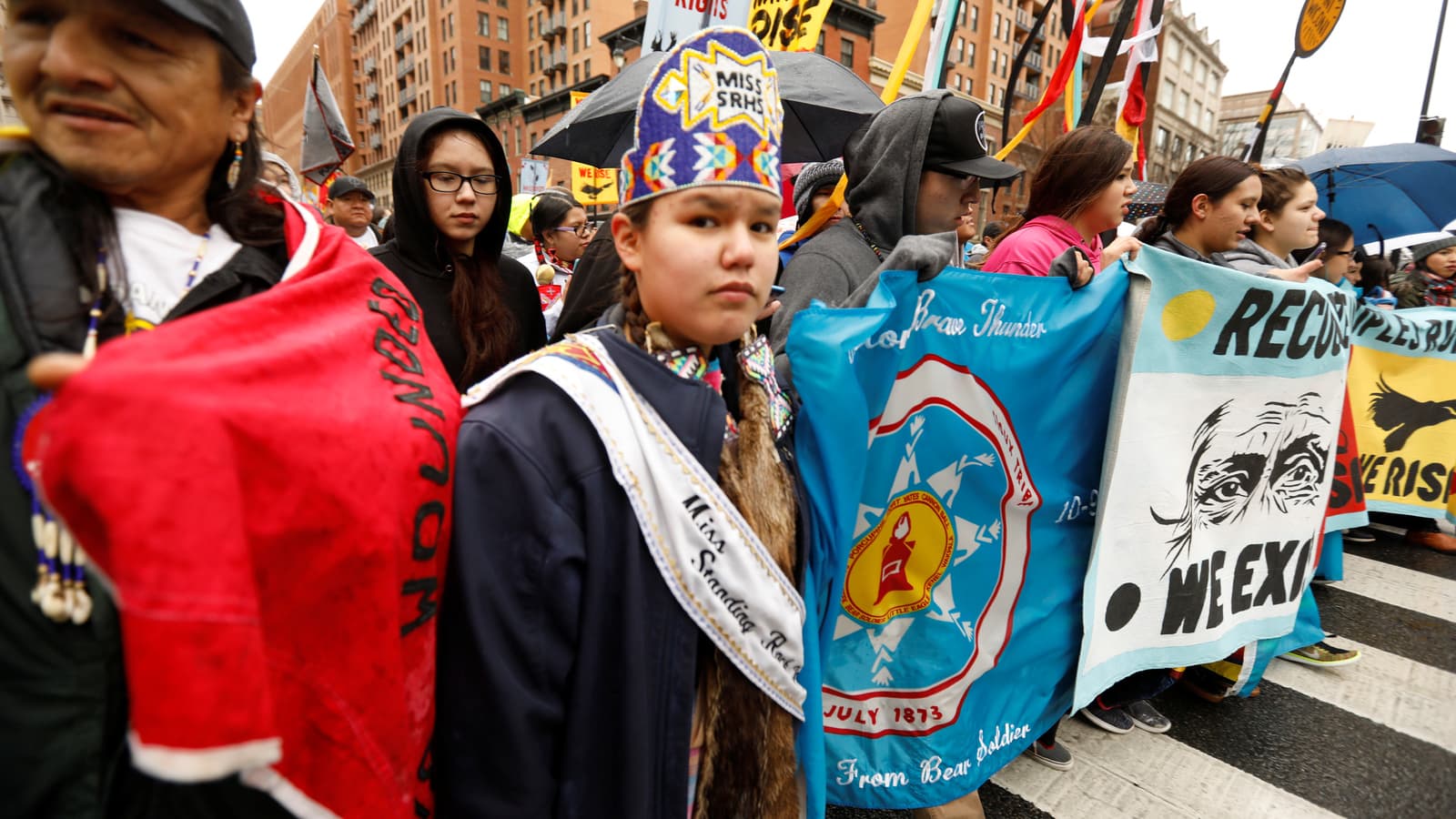 A young woman wearing a purple headdress marches in a rally with Standing Rock Sioux Nation