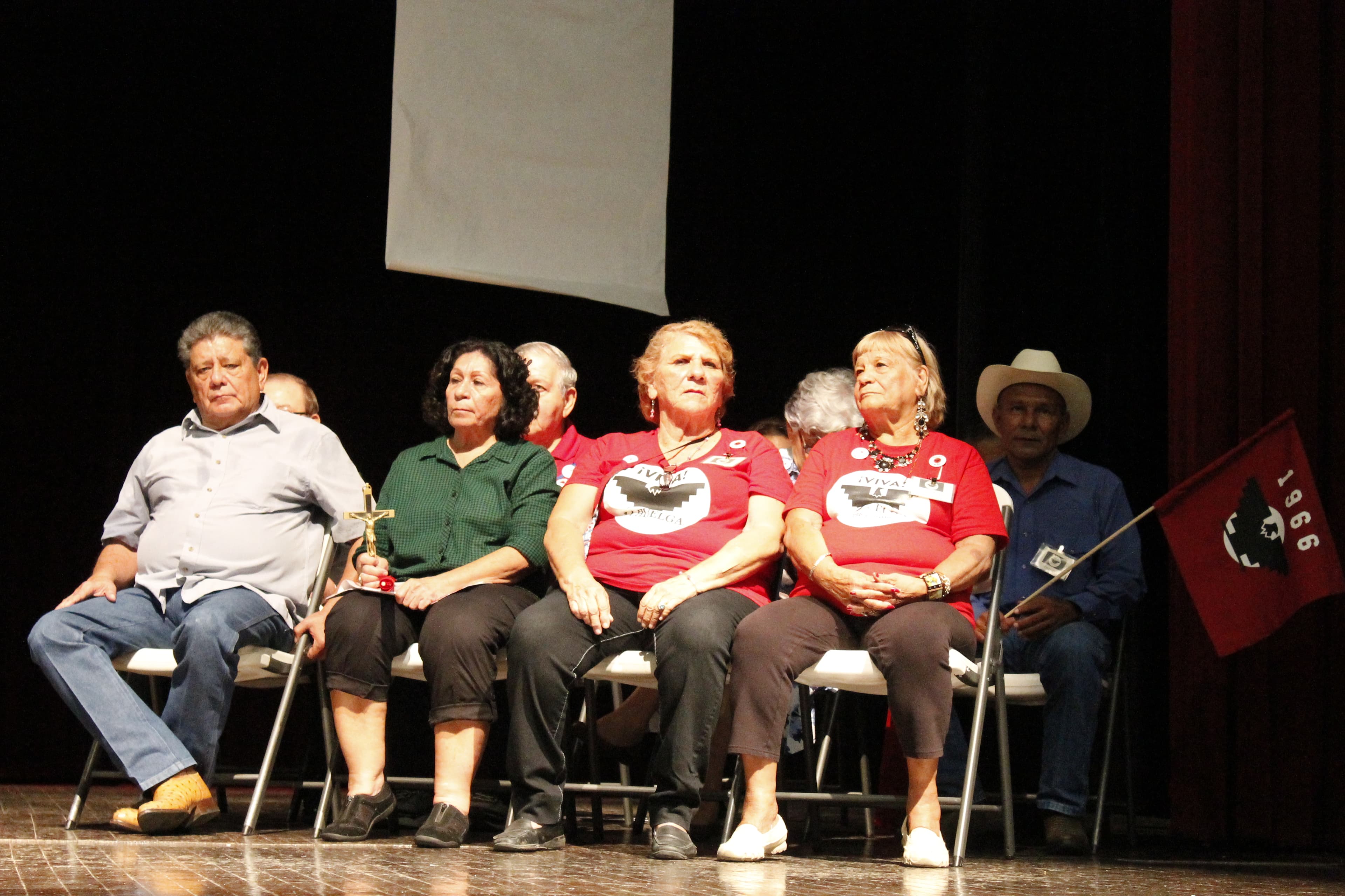 Four people sit on chairs on a stage